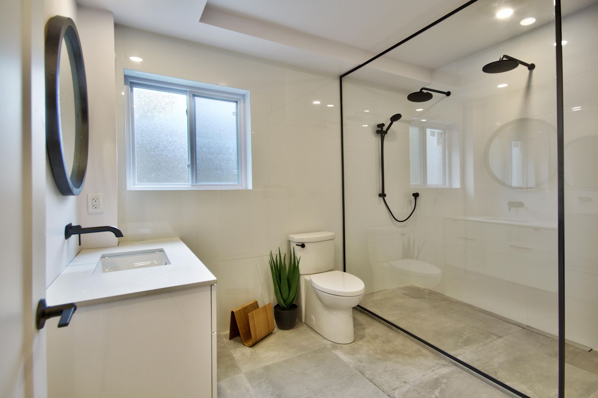 A bathroom with a toilet , sink , shower and window.