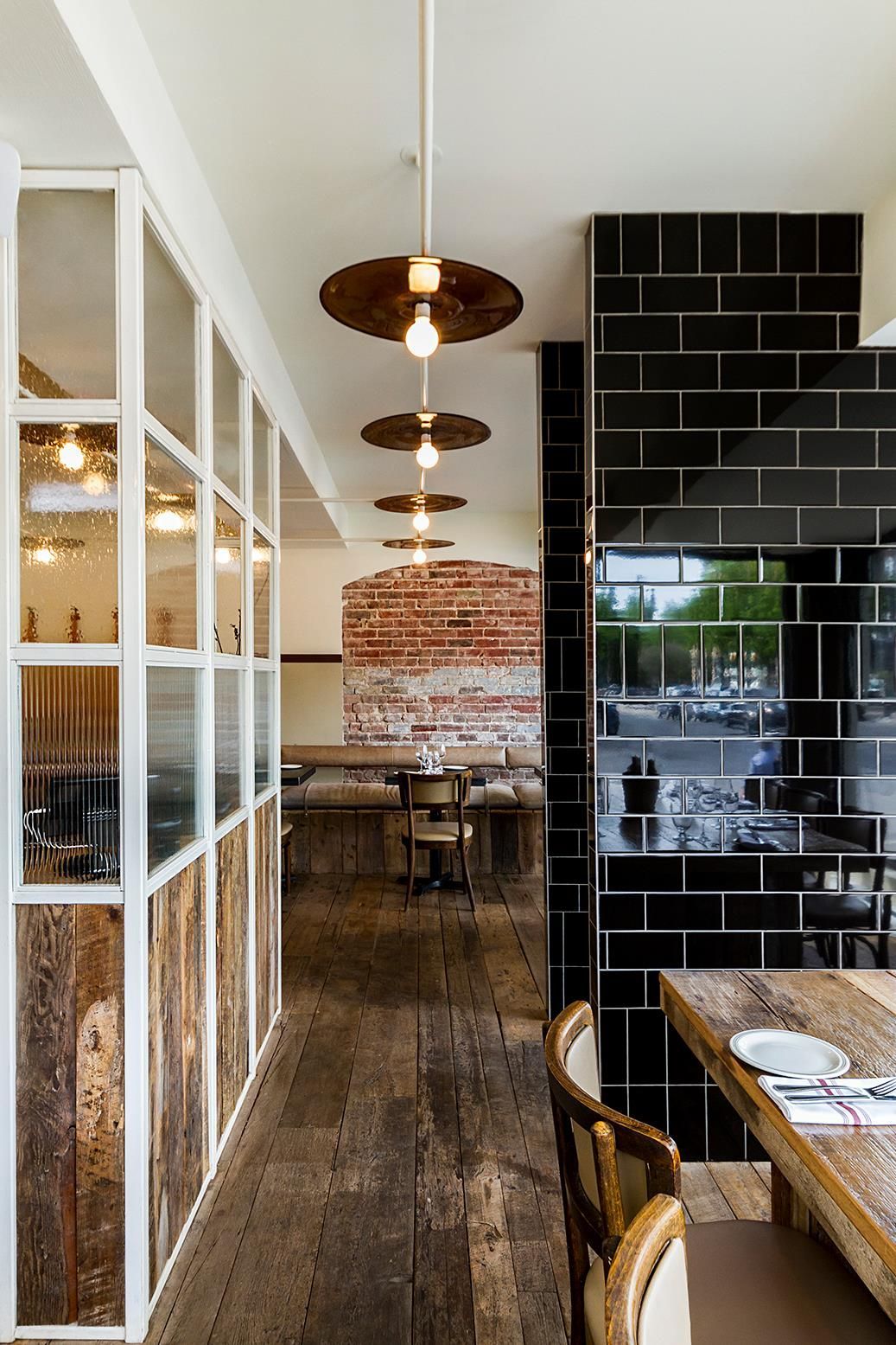 A long hallway leading to a restaurant with tables and chairs.