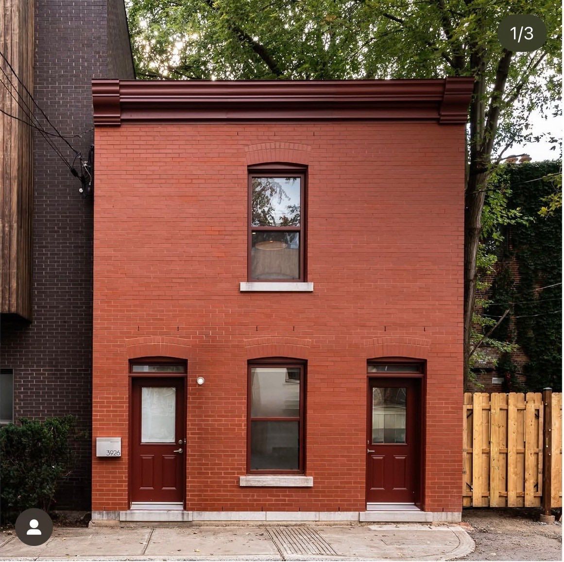 A small red brick building with two doors and two windows.
