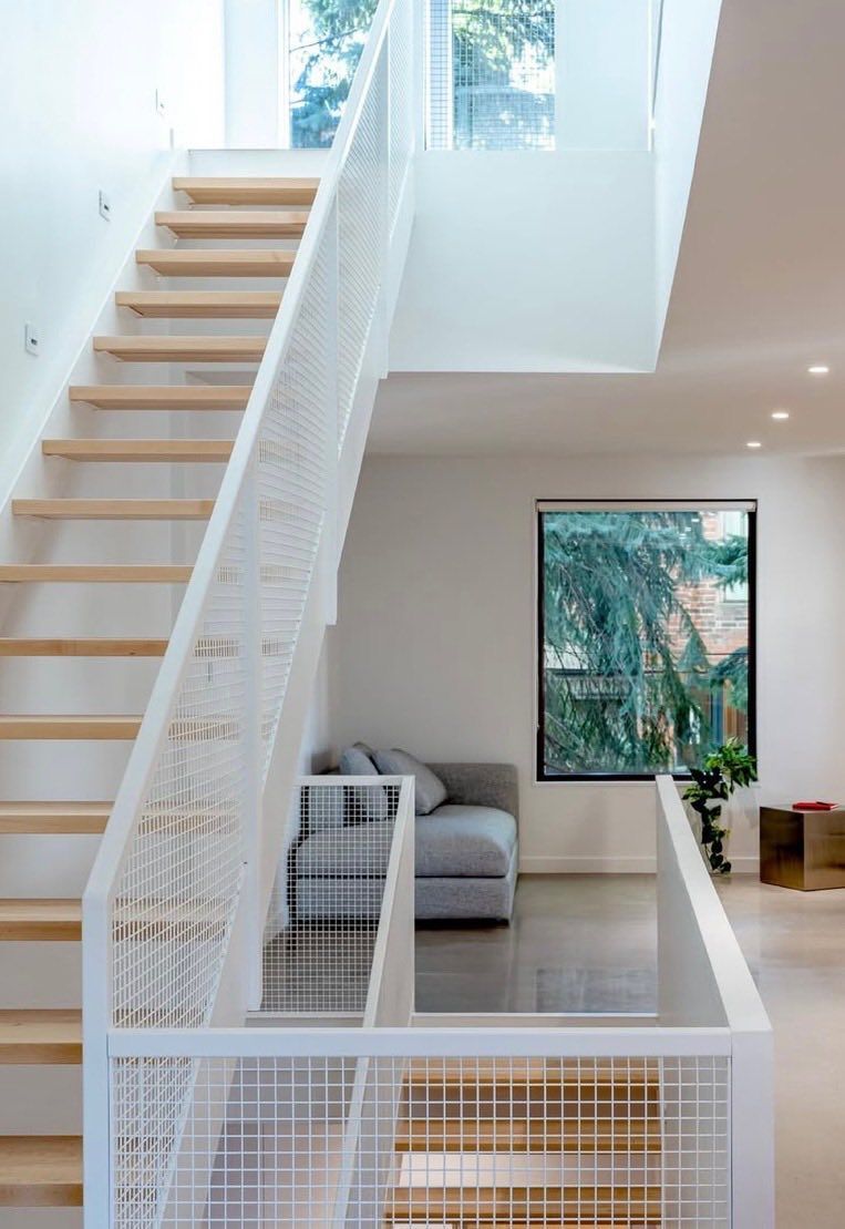A modern staircase with wooden steps and a white railing in a living room.