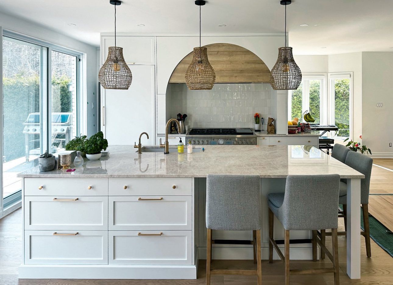 A kitchen with white cabinets , granite counter tops , stools and a large island.