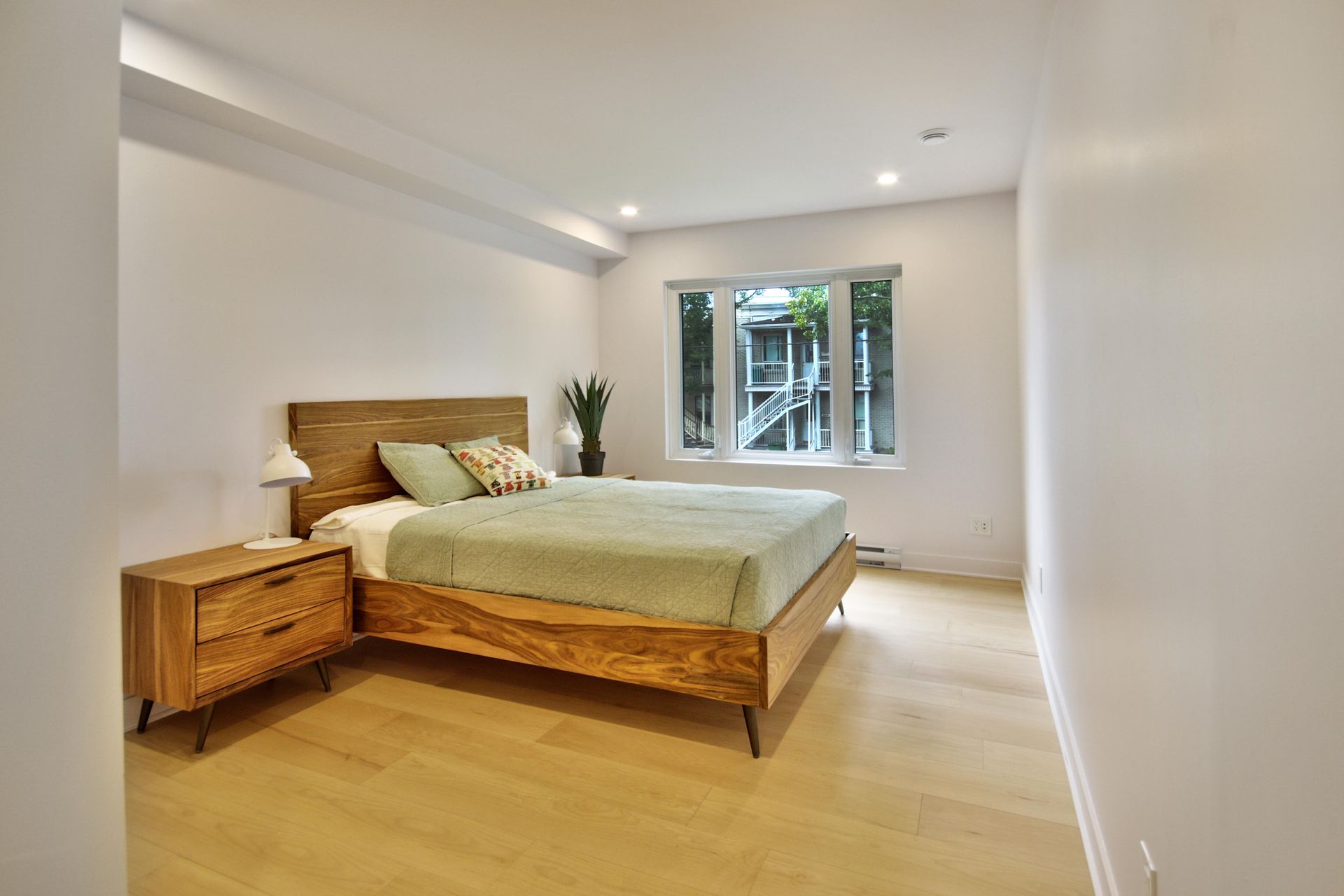 A bedroom with a bed , nightstand , and window.