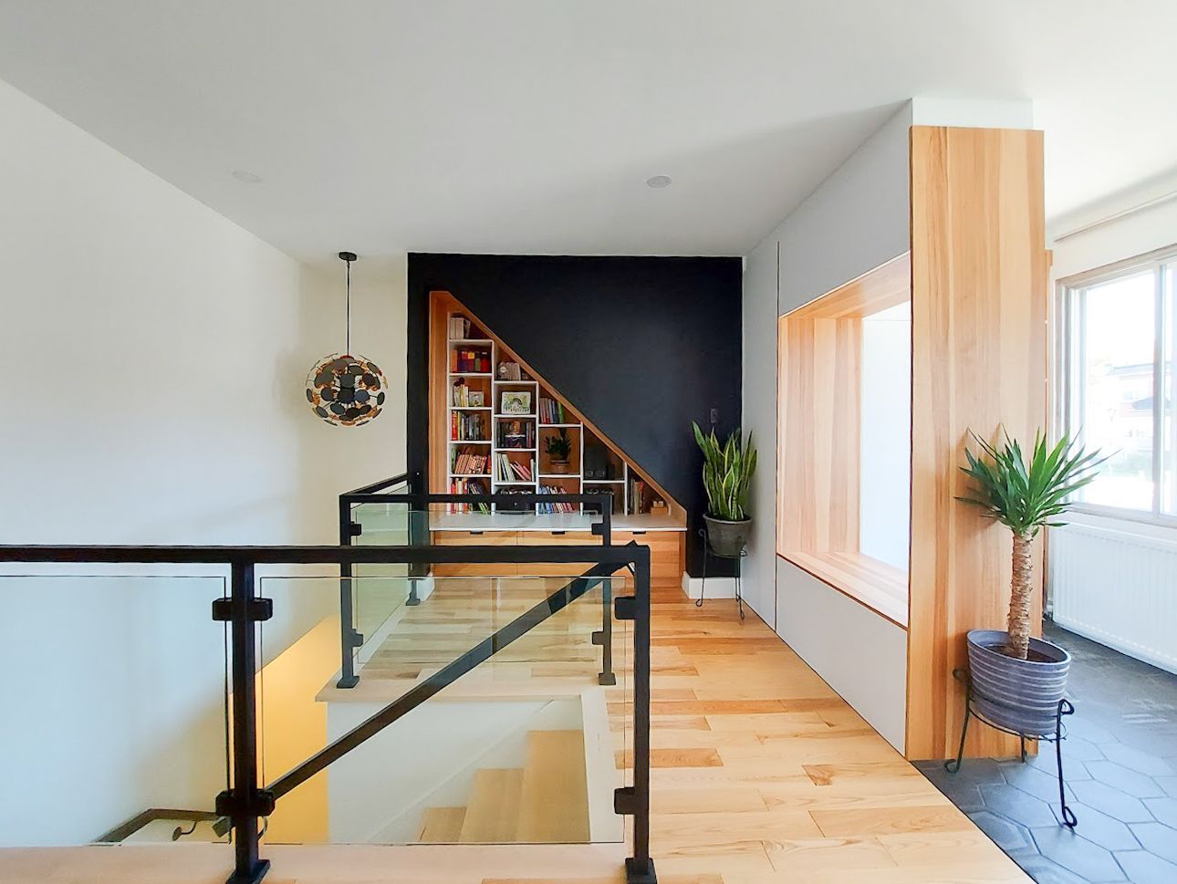 A staircase with a glass railing and a bookshelf underneath it.