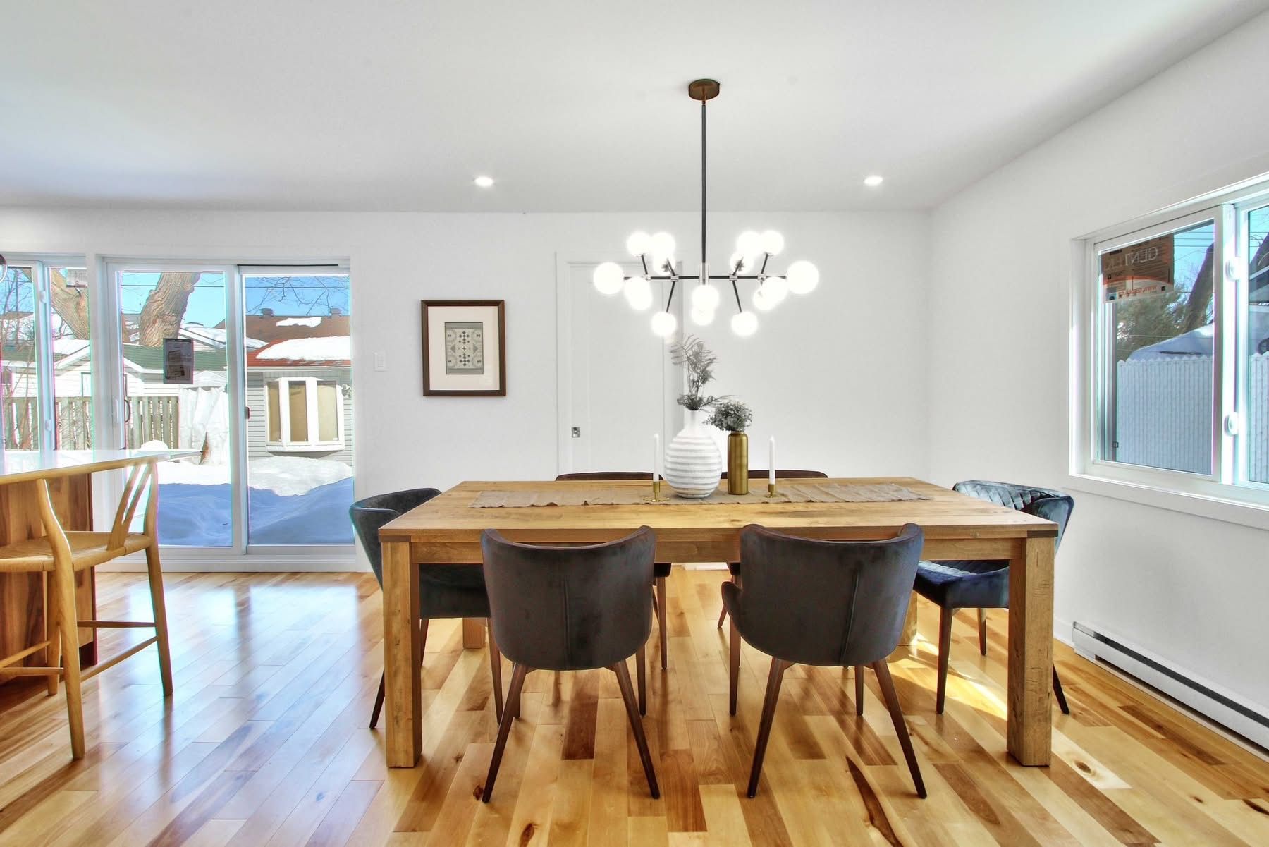 A dining room with a wooden table and chairs and a chandelier.