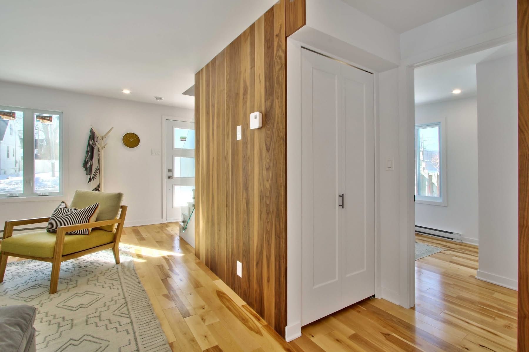 A living room with hardwood floors , a yellow chair and a wooden wall.