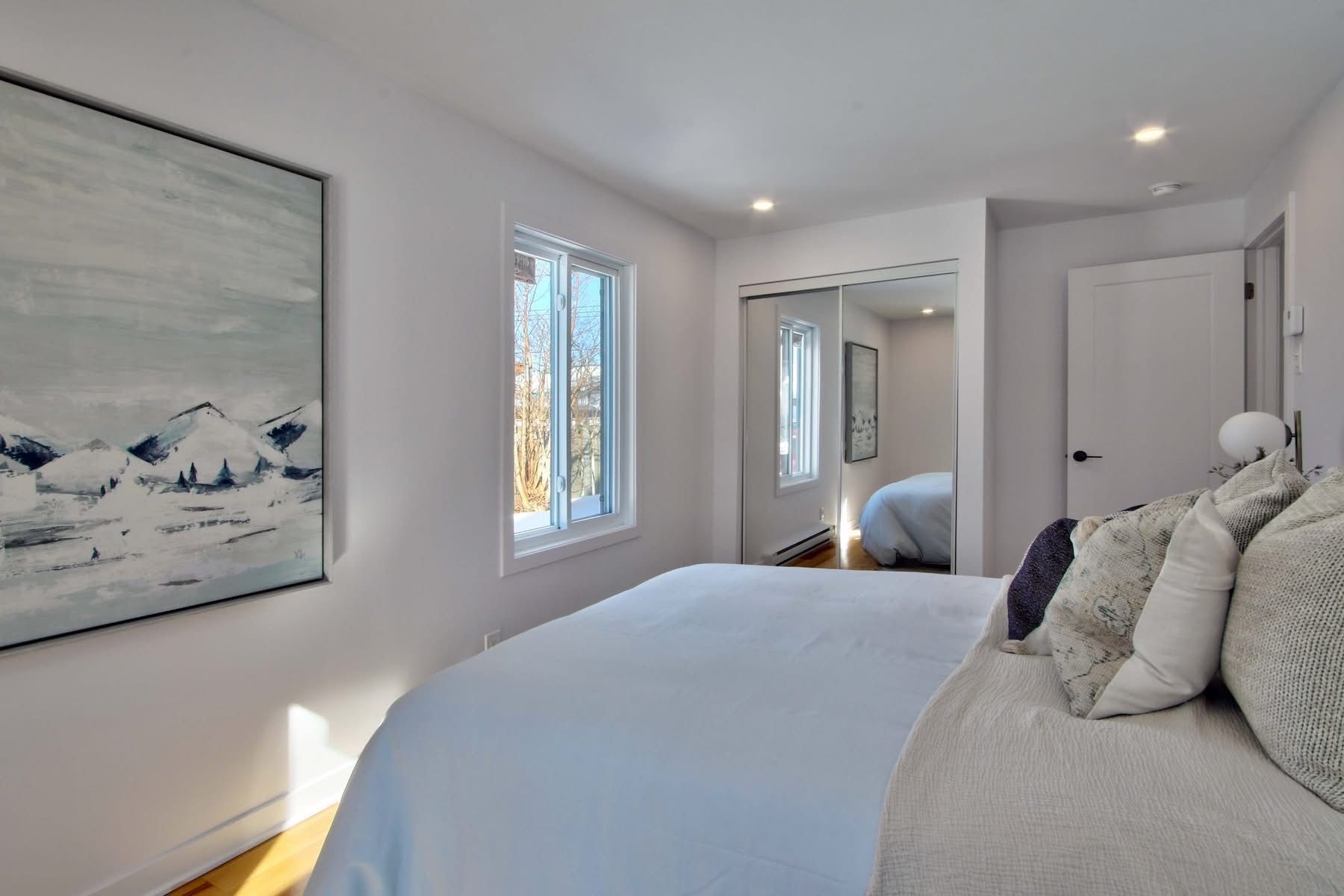 A bedroom with a large bed and a painting on the wall.