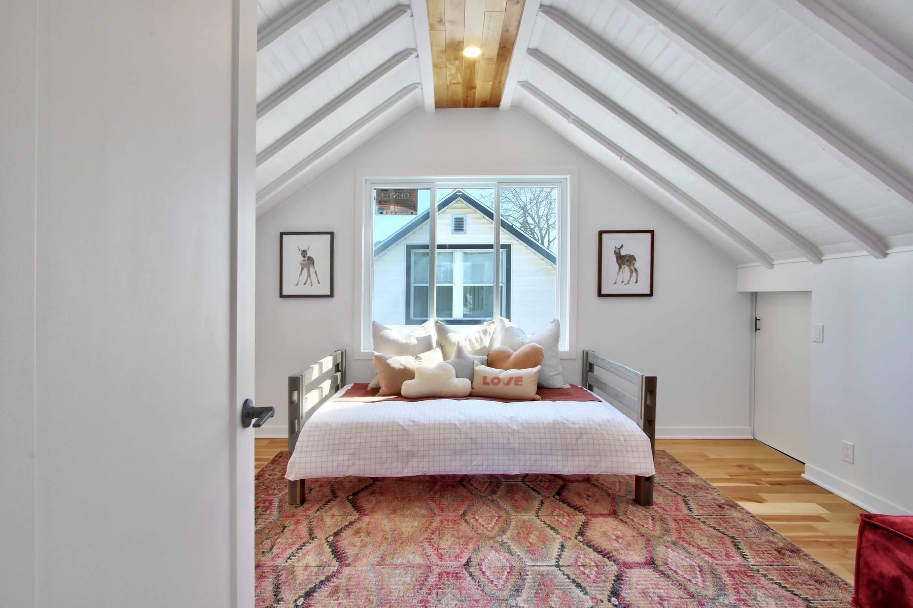 A bedroom with a bed and a rug in the attic.
