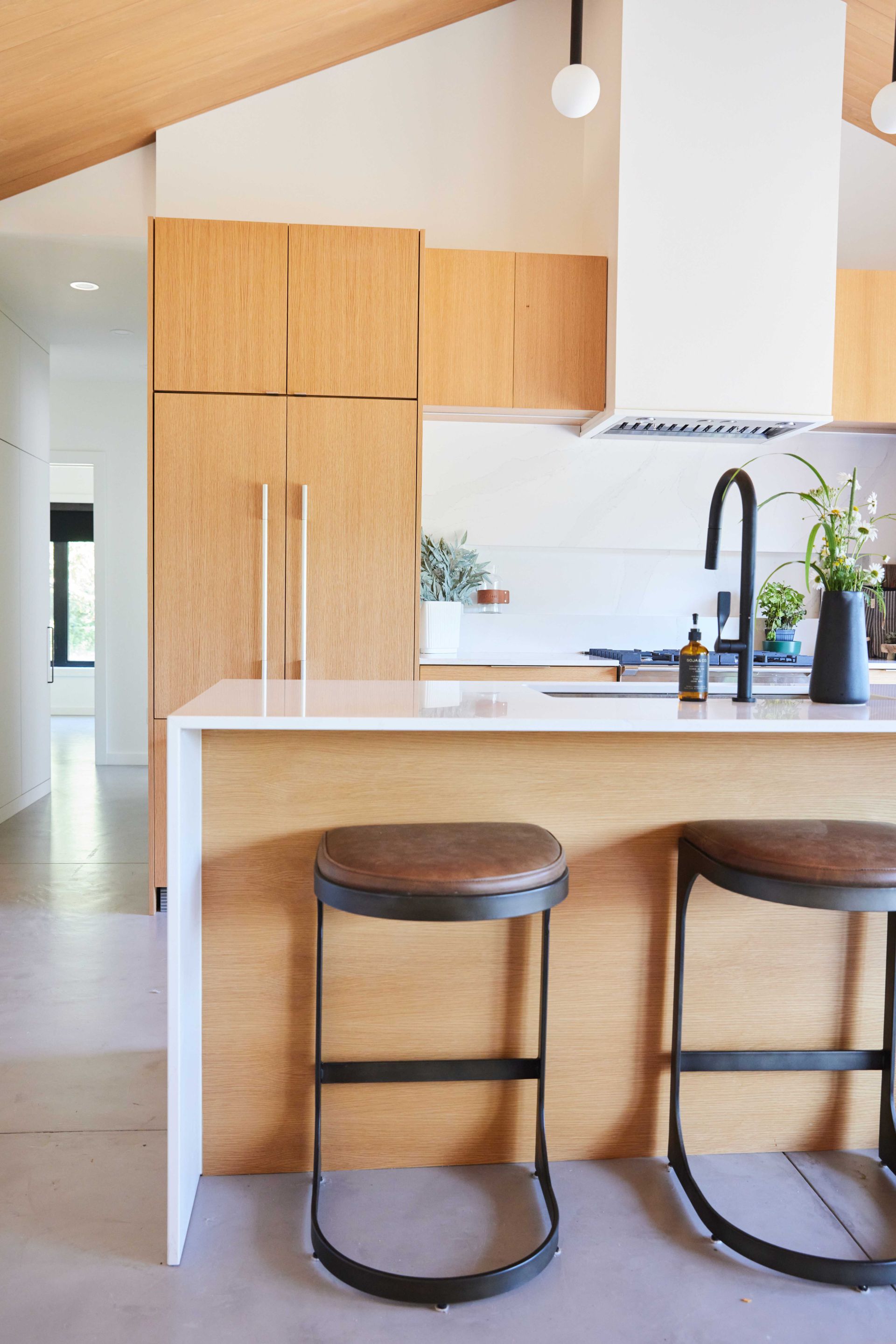 A kitchen with a wooden island and two bar stools.