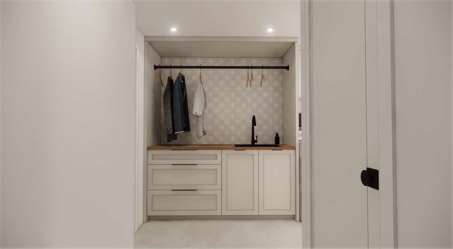 A laundry room with white cabinets and a sink.