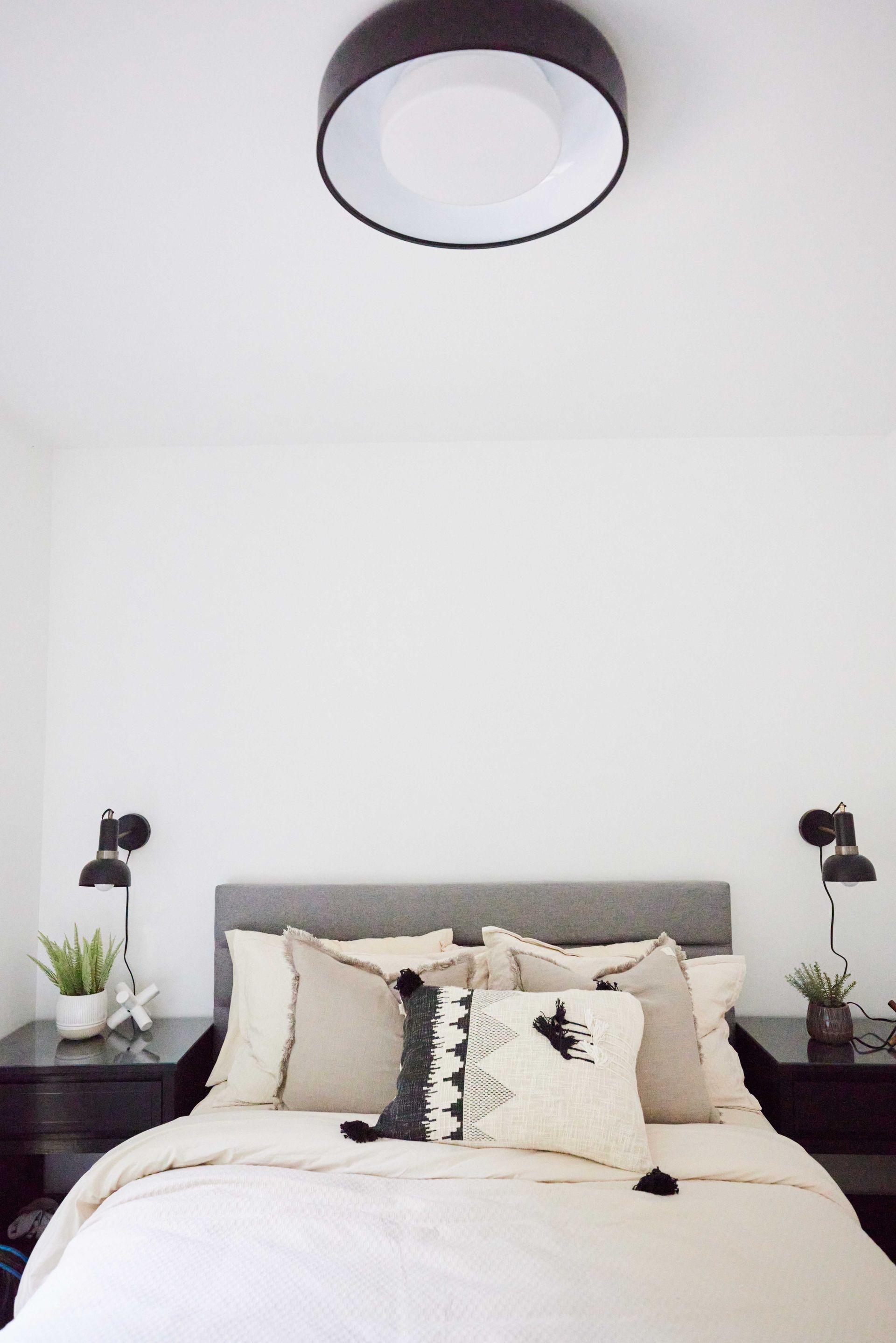 A bedroom with a bed , nightstands , and a ceiling light.