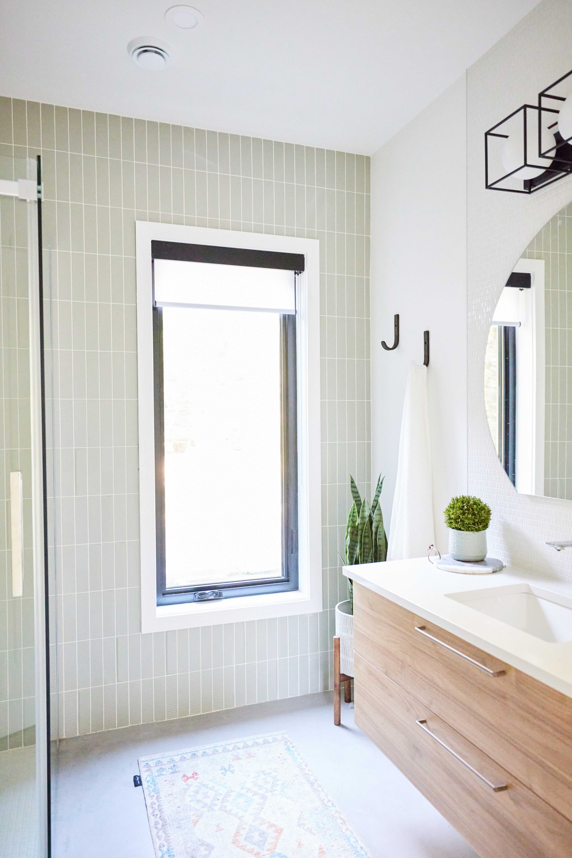 A bathroom with a sink , mirror and window.
