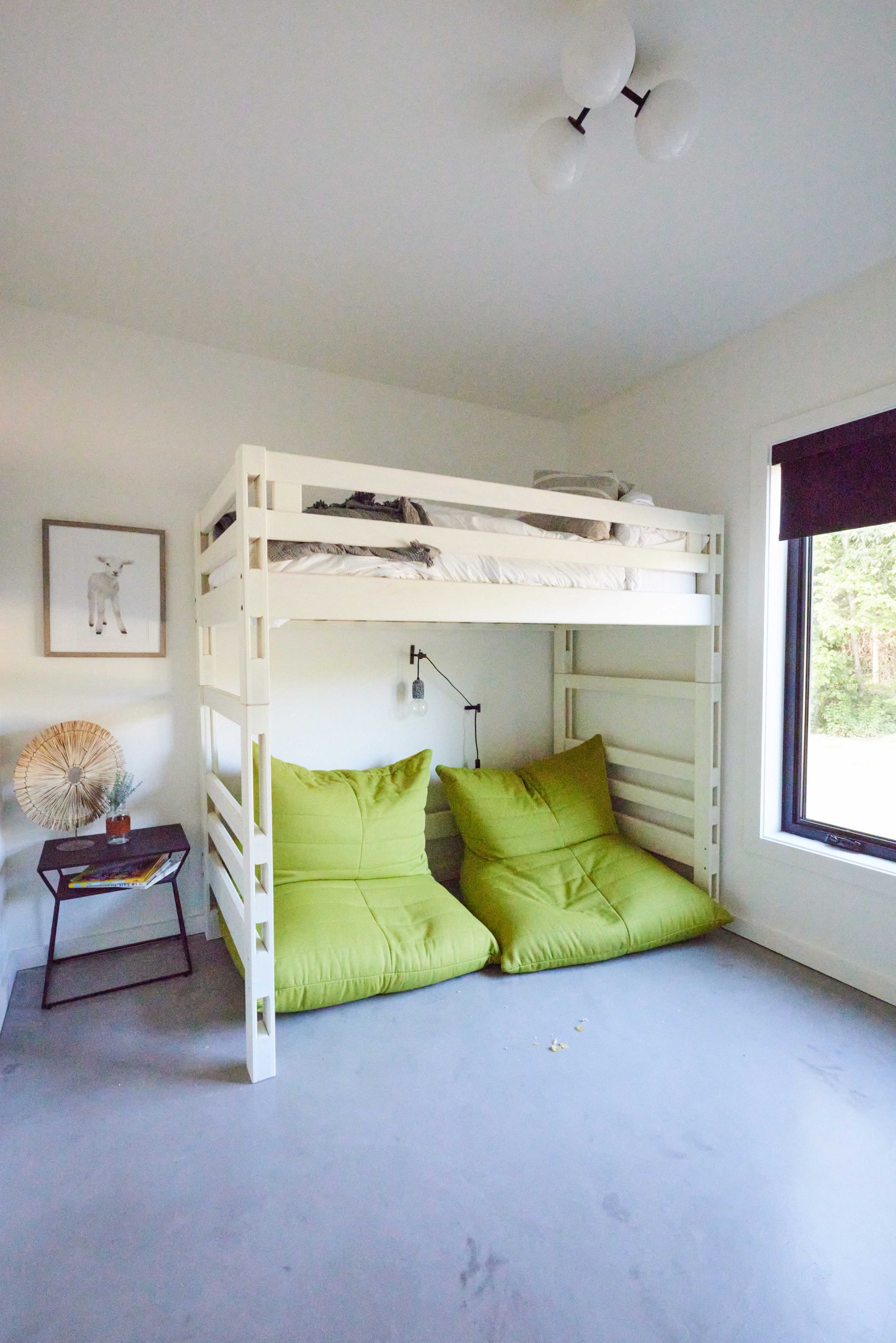 A bunk bed with green pillows underneath it in a bedroom.