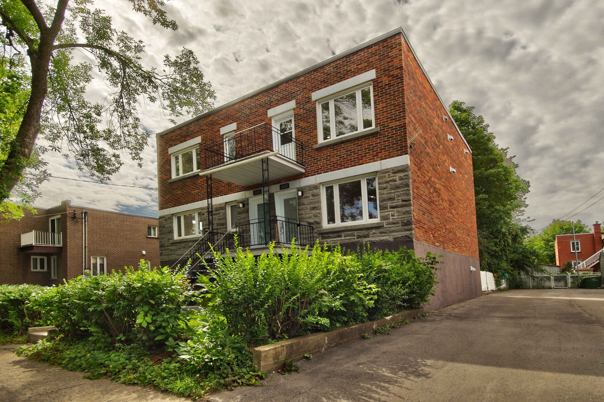 A brick building with a lot of windows and bushes in front of it