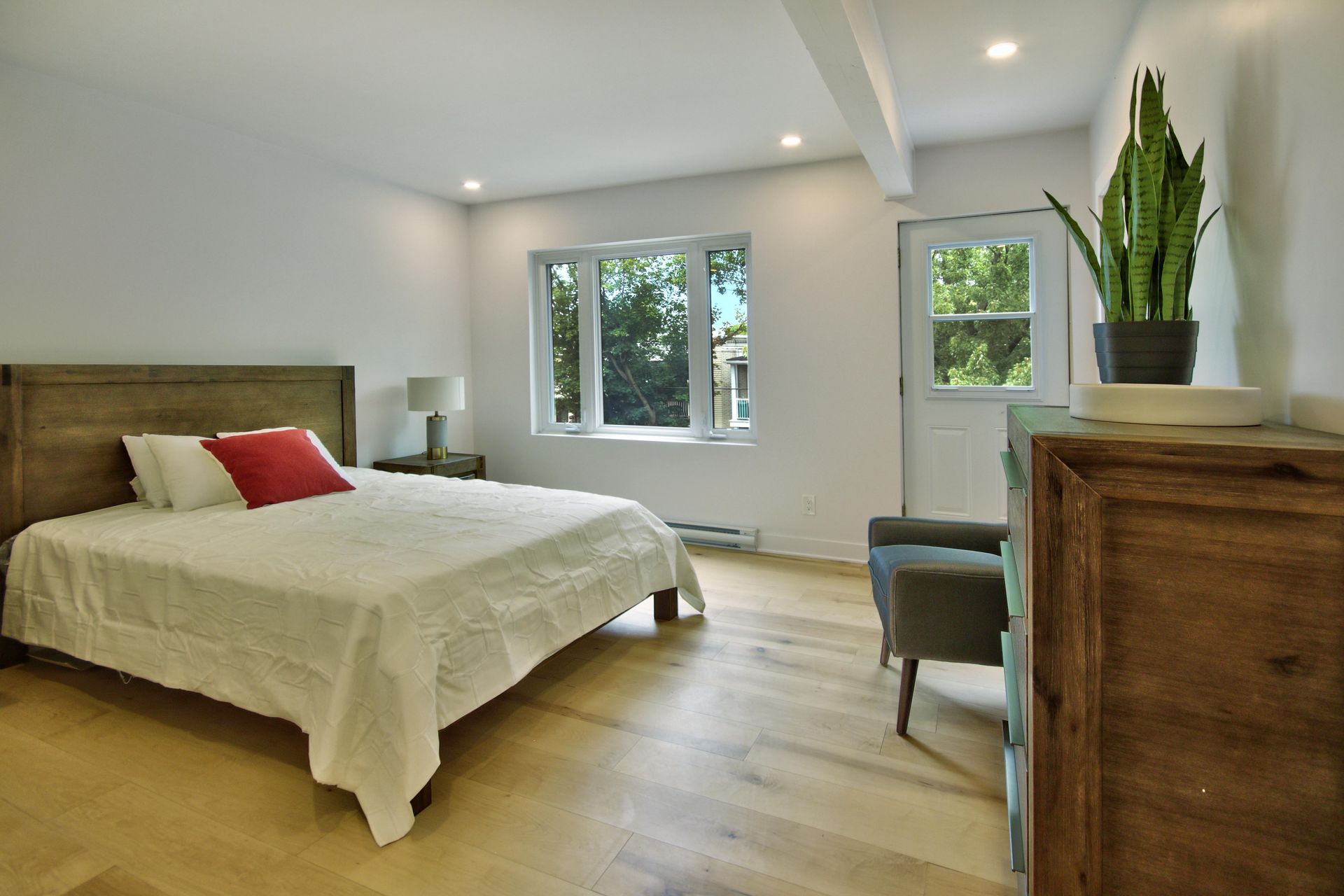 A bedroom with a bed , dresser , chair and window.