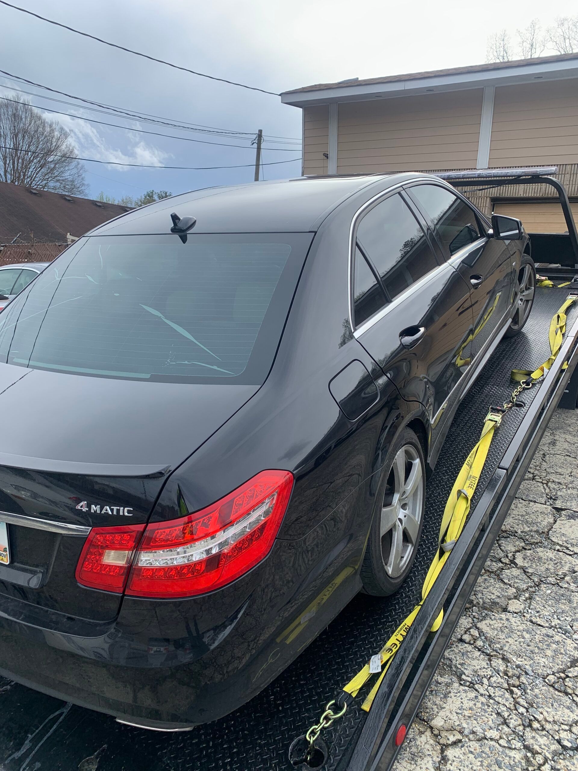 A black car is sitting on top of a tow truck.