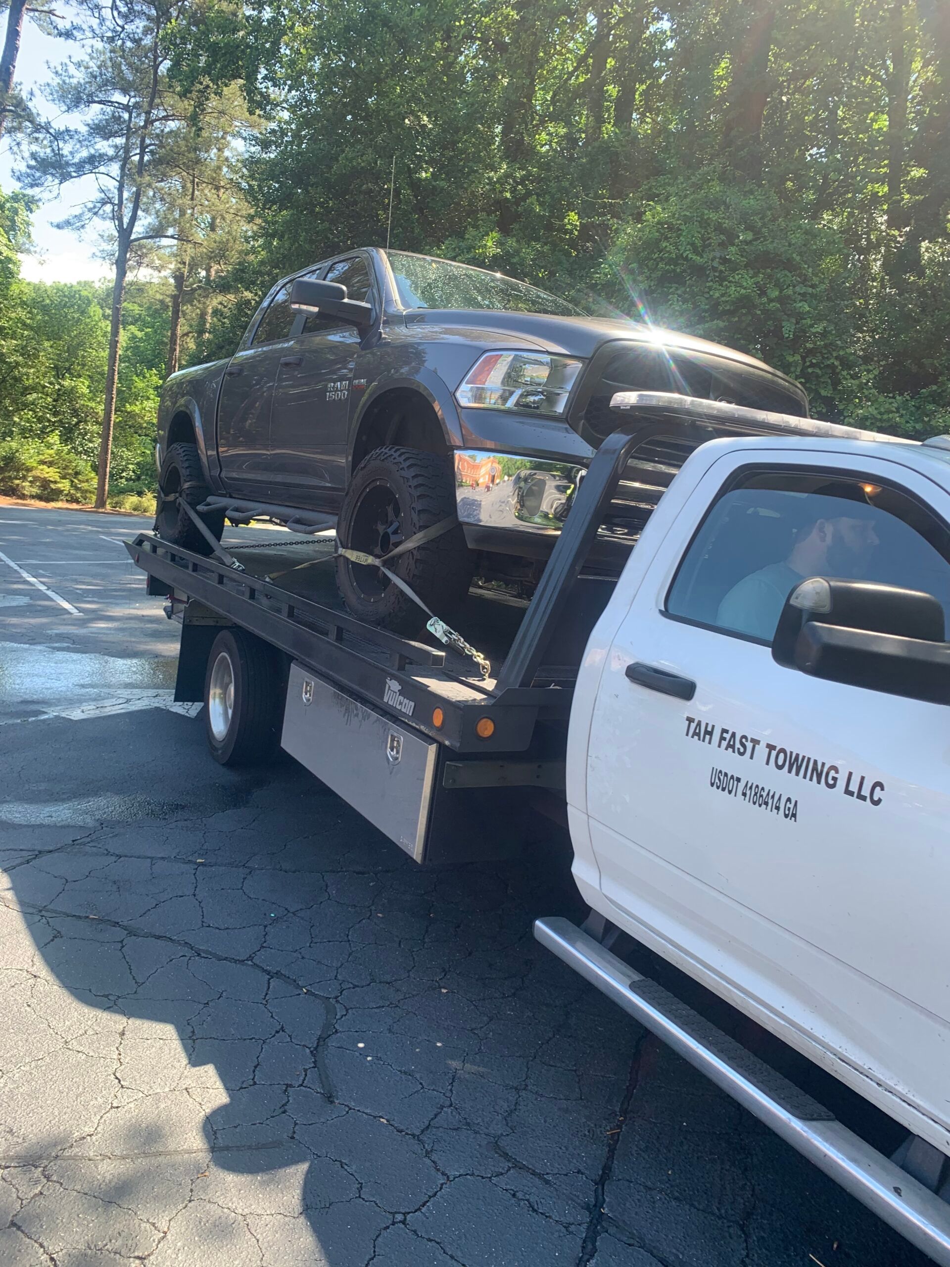 A black car is being towed by a tow truck.