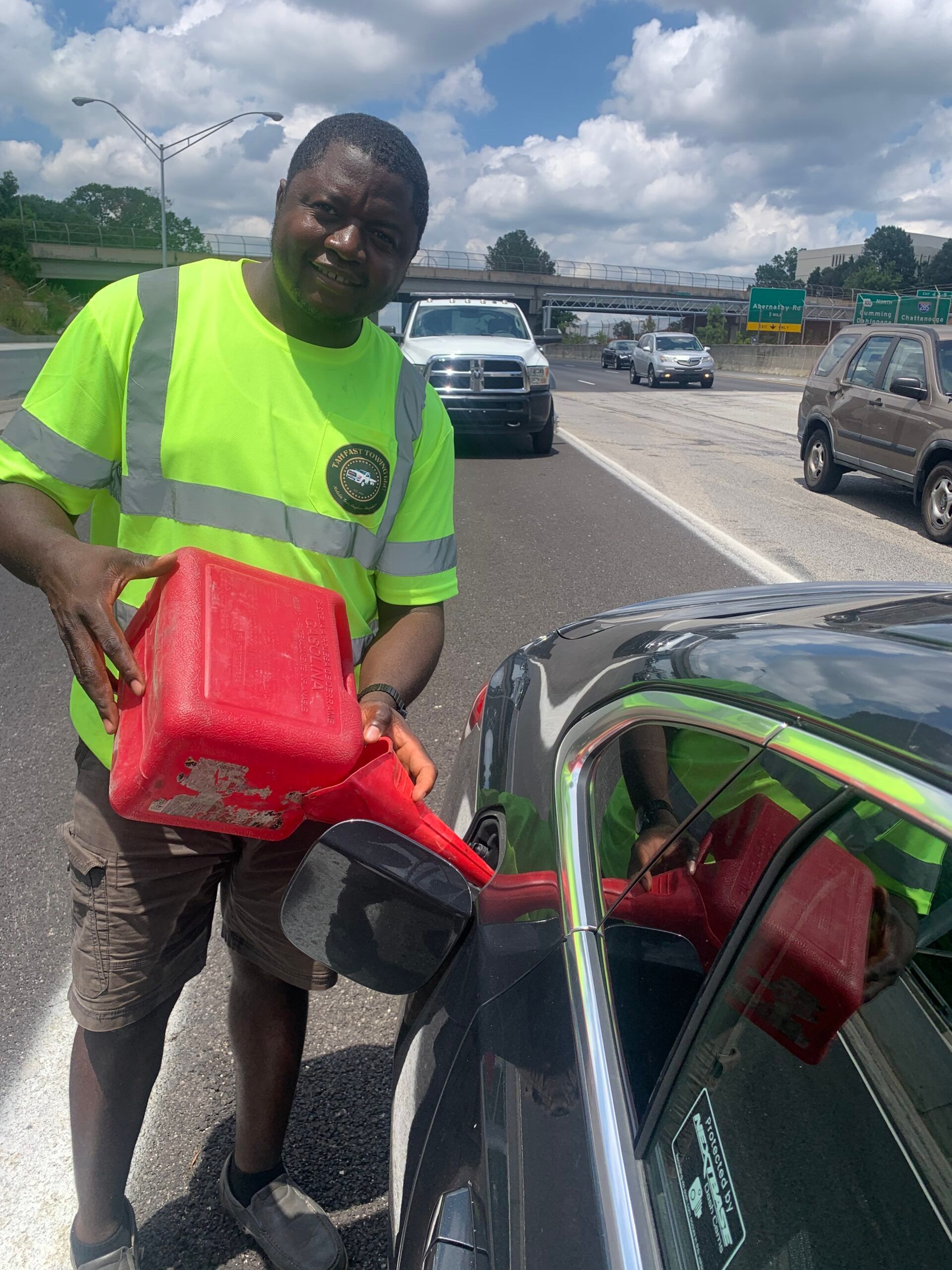 A man is standing next to a car holding a red gas can.