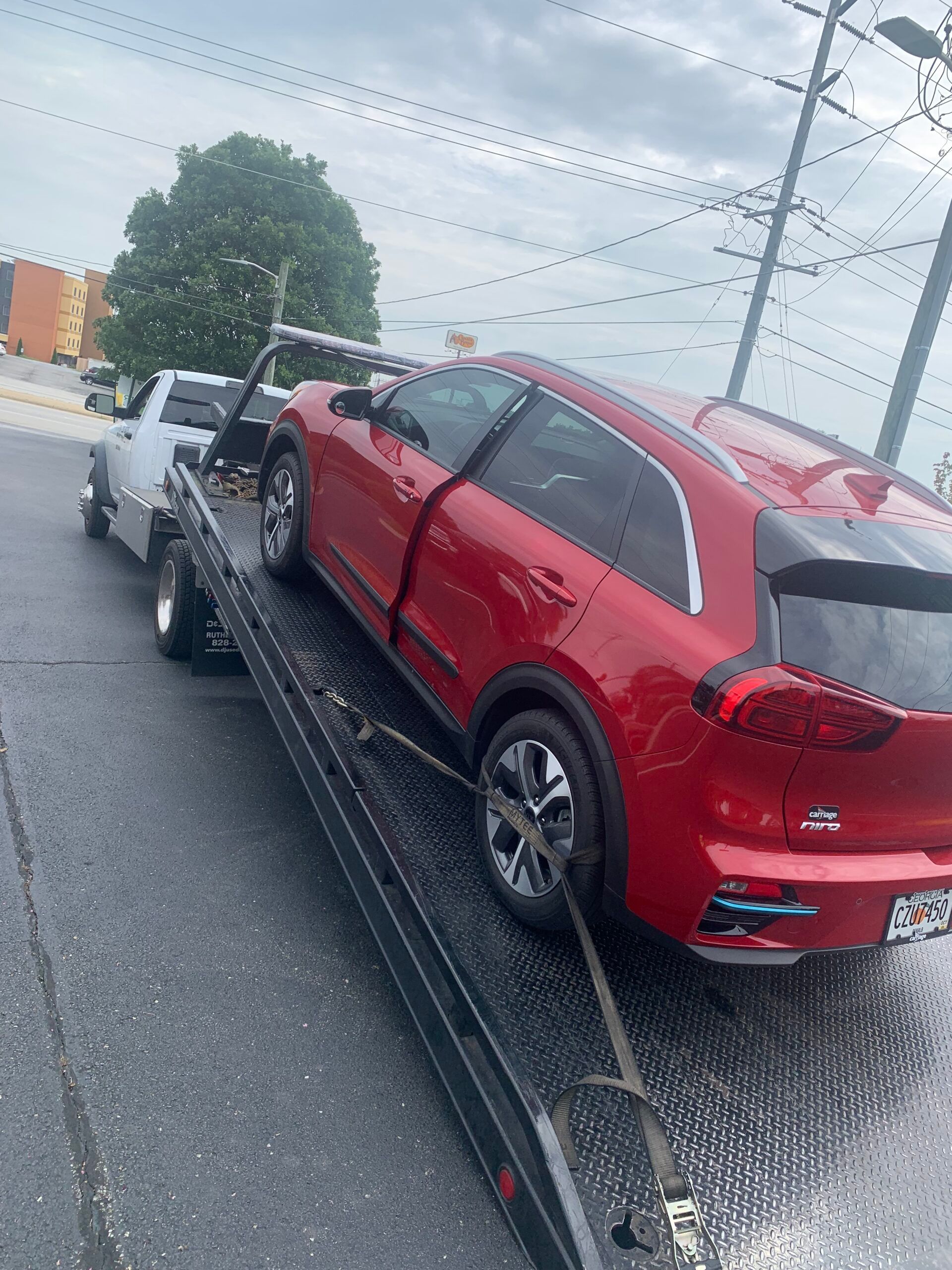 A red car is being towed by a tow truck.