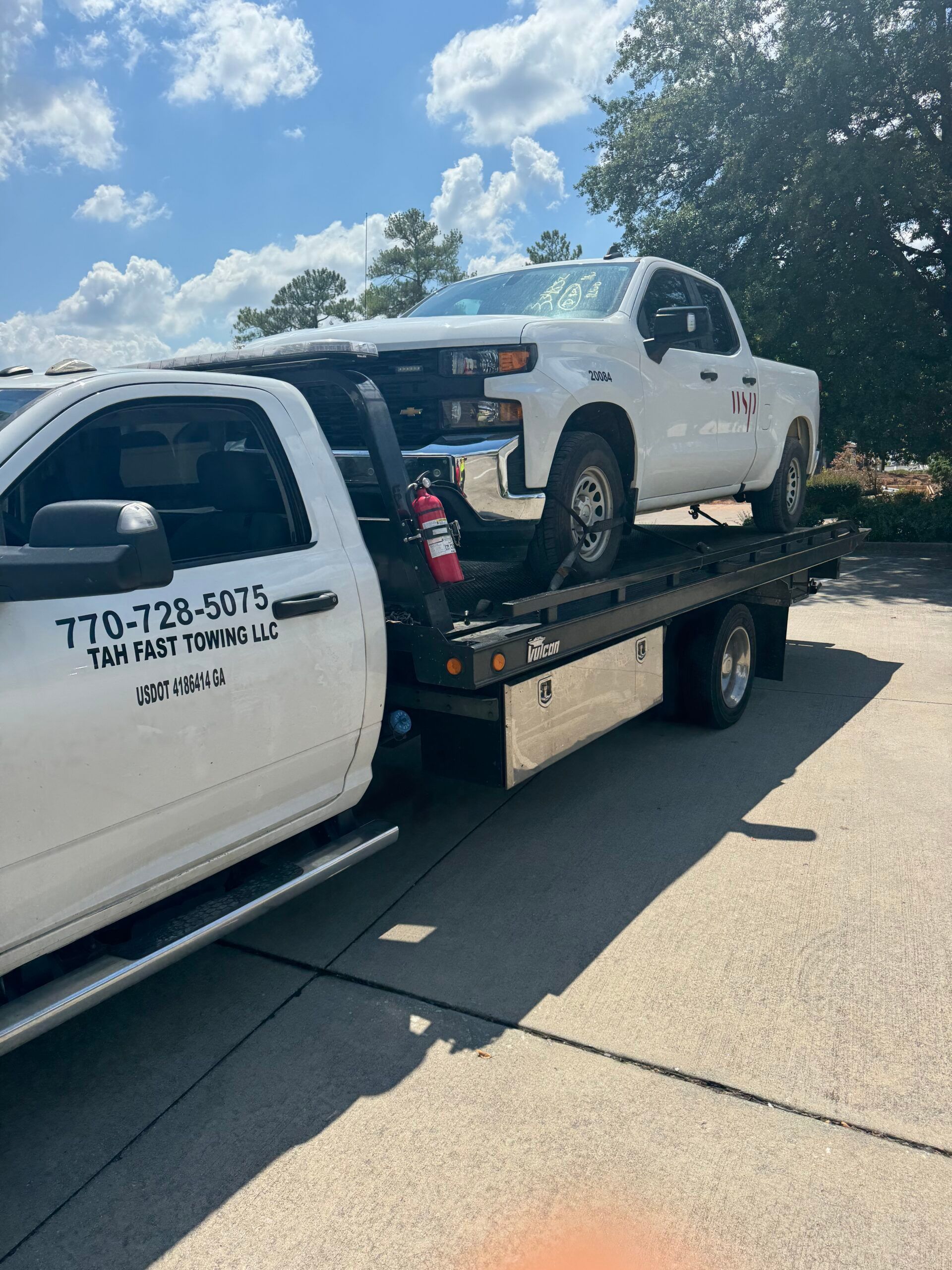 A white truck is being towed by a tow truck.