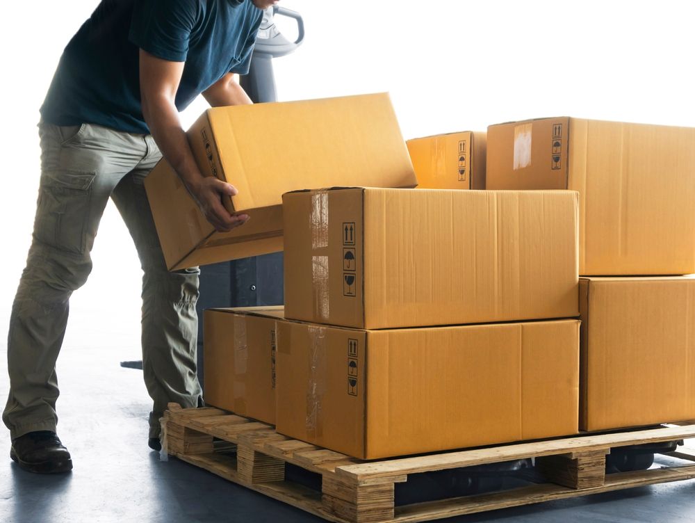 Man Loading Boxes Onto a Wooden Pallet With a Forklift in a Warehouse — The Move It Man In Townsville, QLD