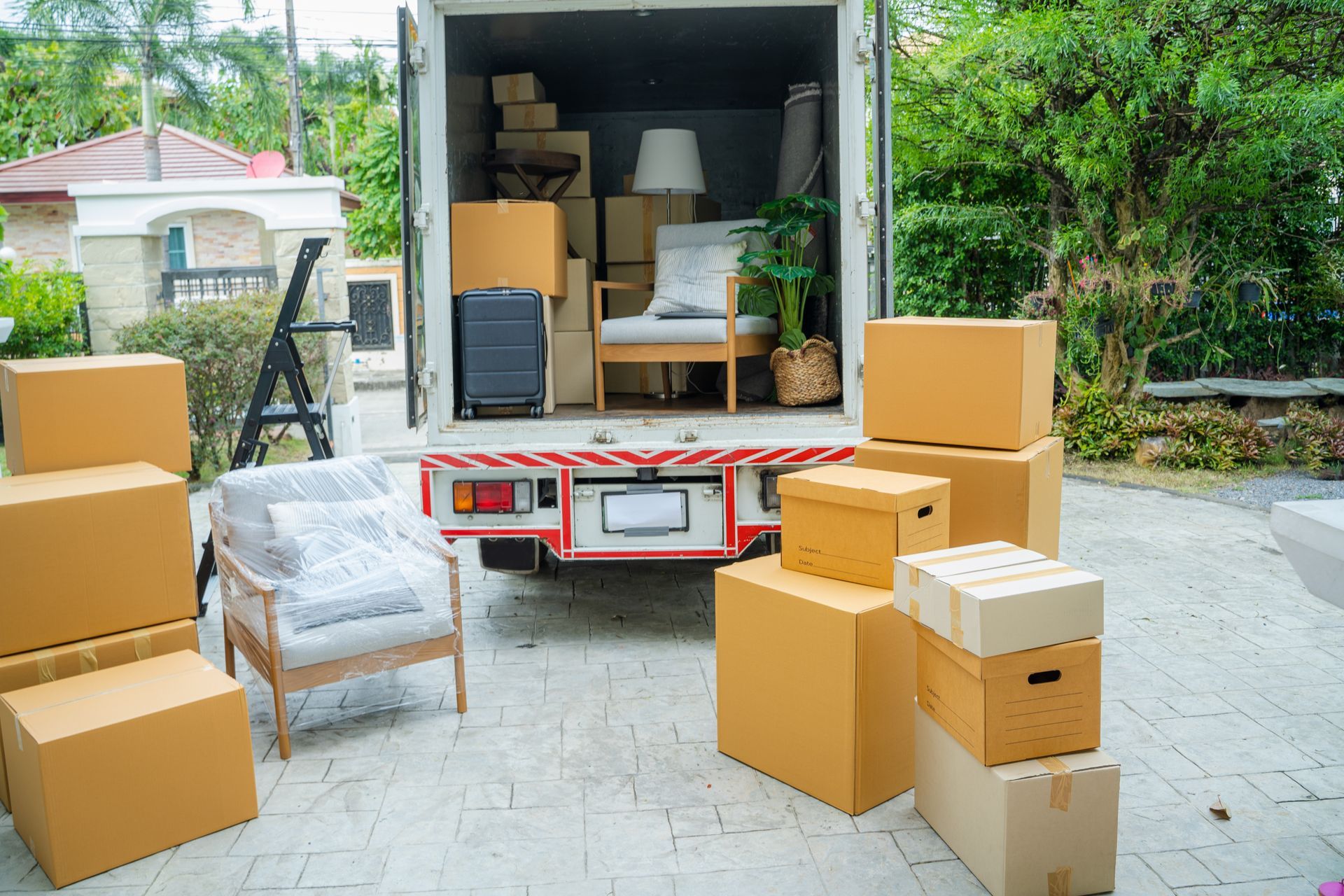 Moving Truck Being Loaded With Furniture and Boxes in a Driveway — The Move It Man In Cairns, QLD