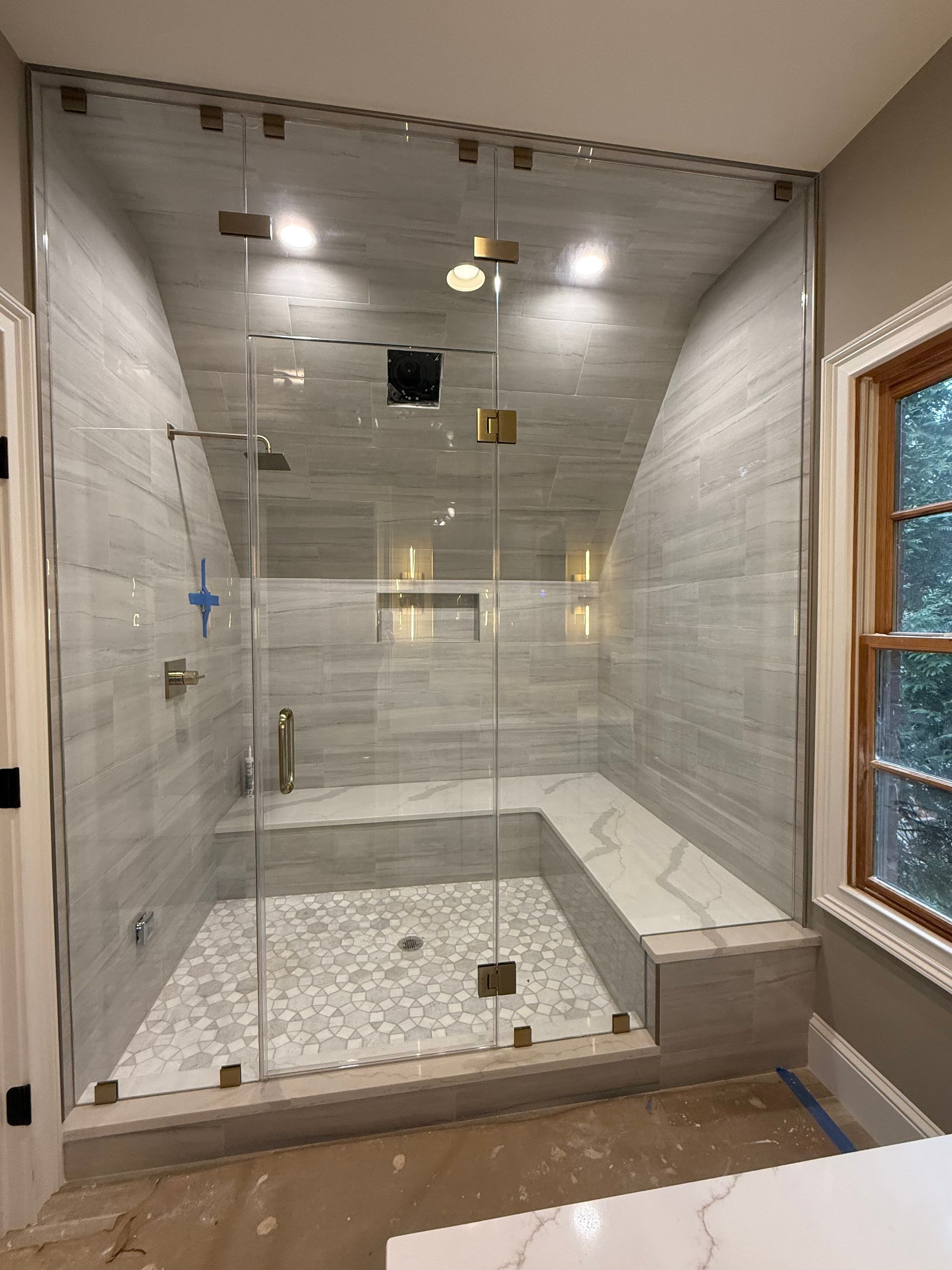A bathroom with a walk in shower and a window.