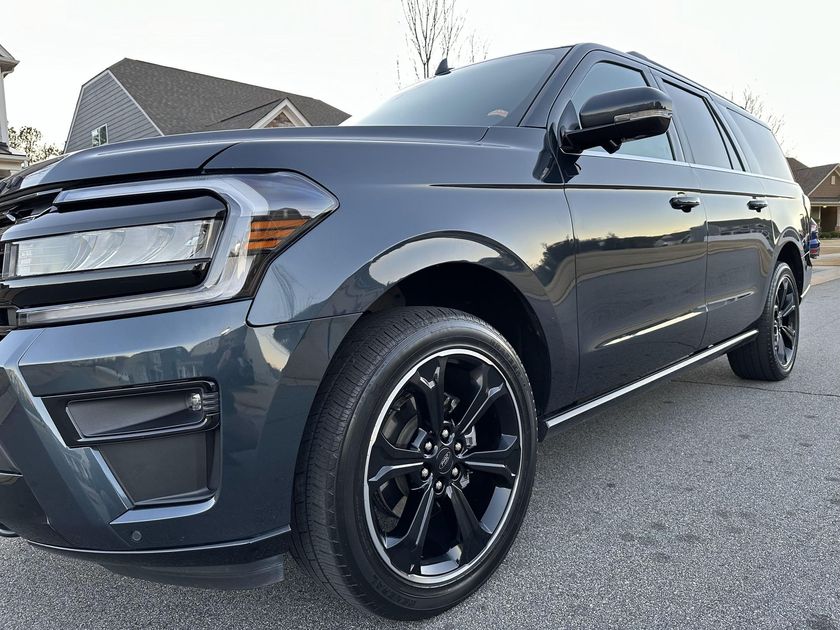 Dark gray Ford Expedition SUV parked on a paved road, daytime.