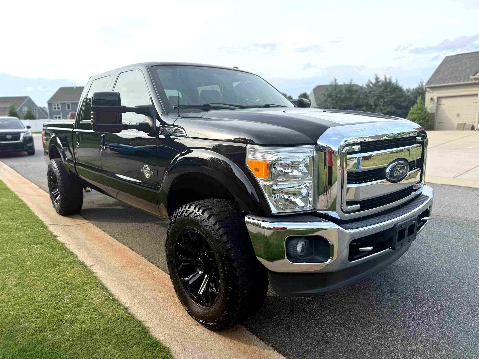 A black ford f250 pickup truck is parked on the side of the road.