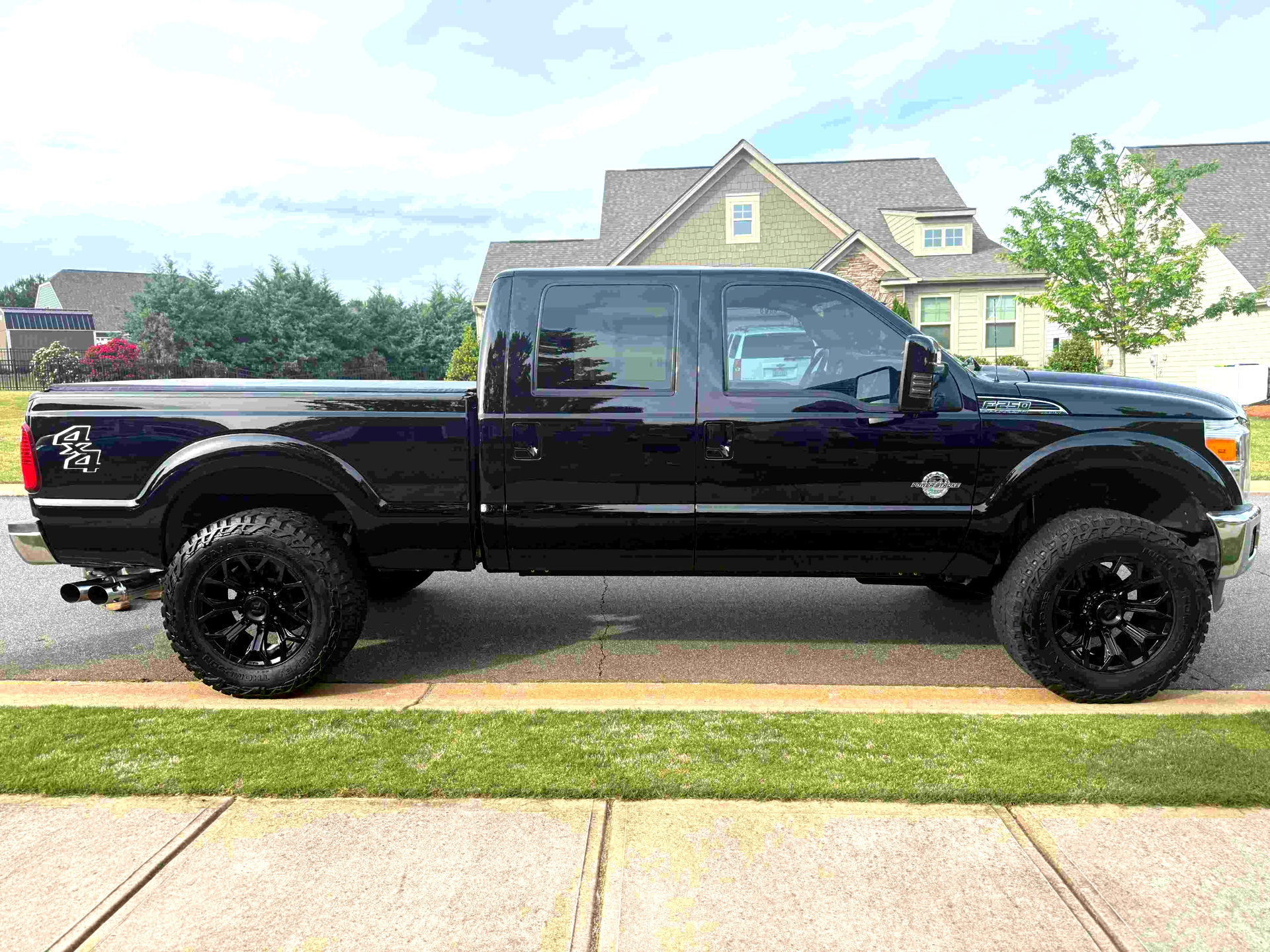 A black pickup truck is parked on the side of the road in front of a house.
