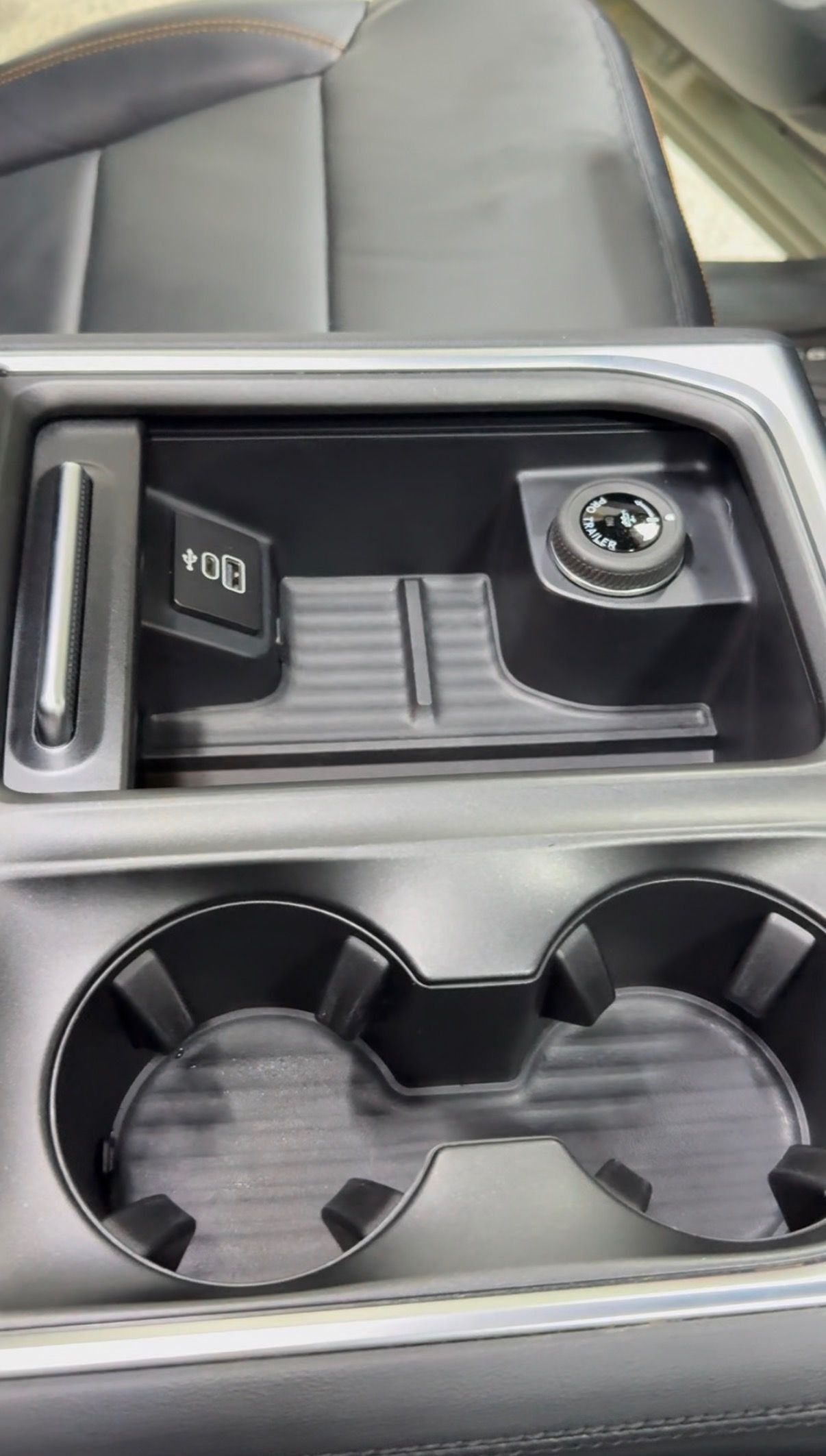 Car center console with wireless charging pad, USB-C port, and dual cup holders.