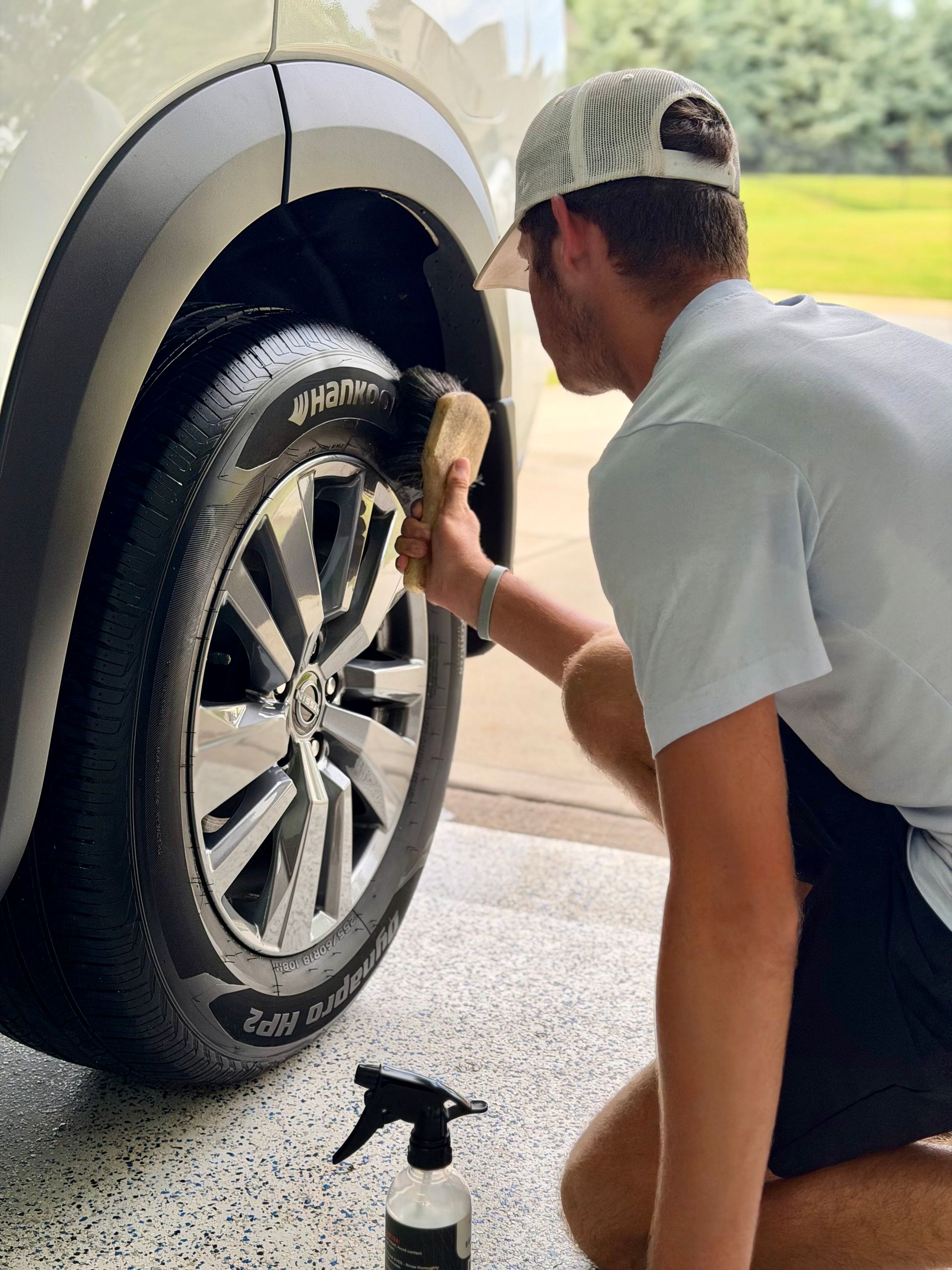 a person wearing black gloves is cleaning a car with a towel .