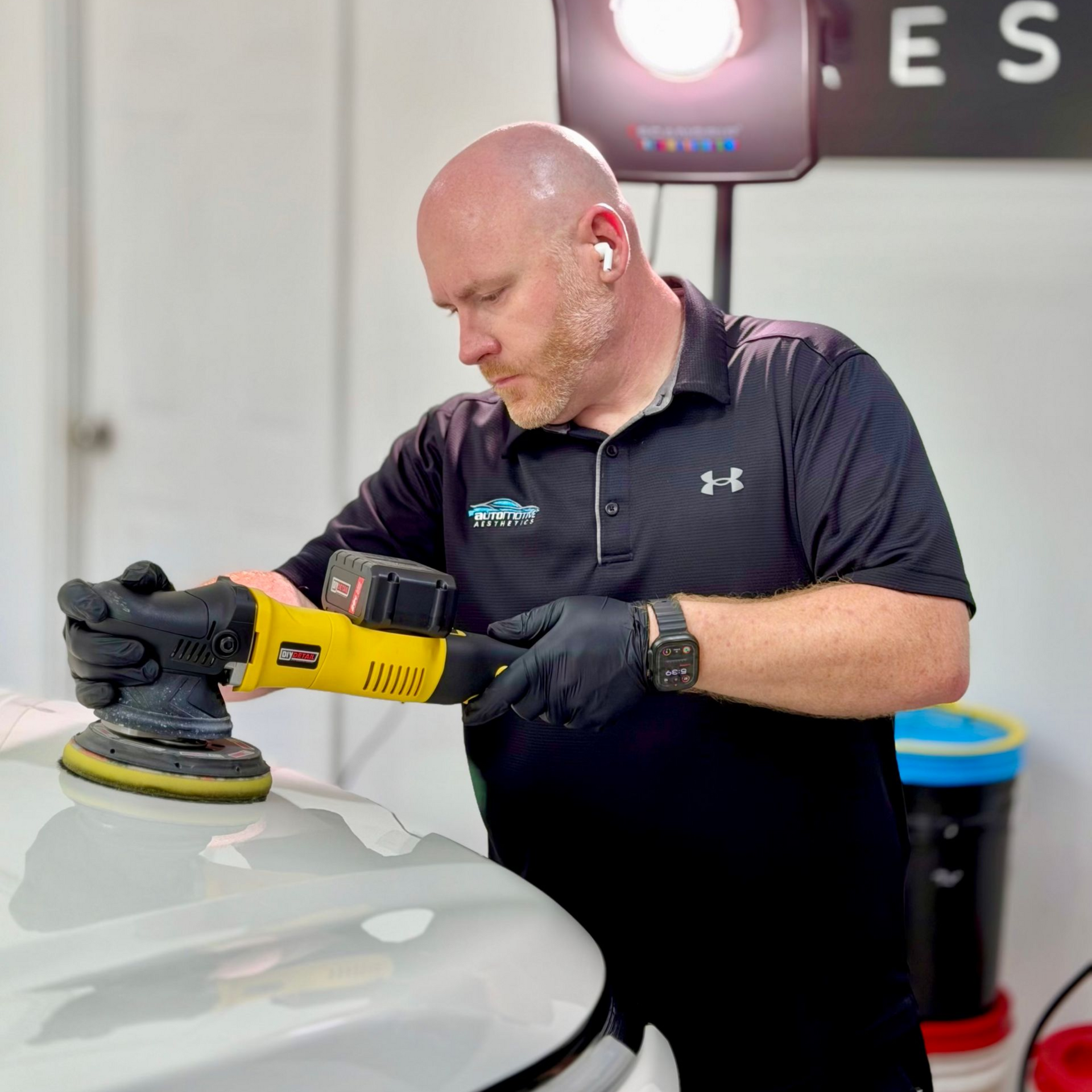 a man is polishing the hood of a car with a machine .