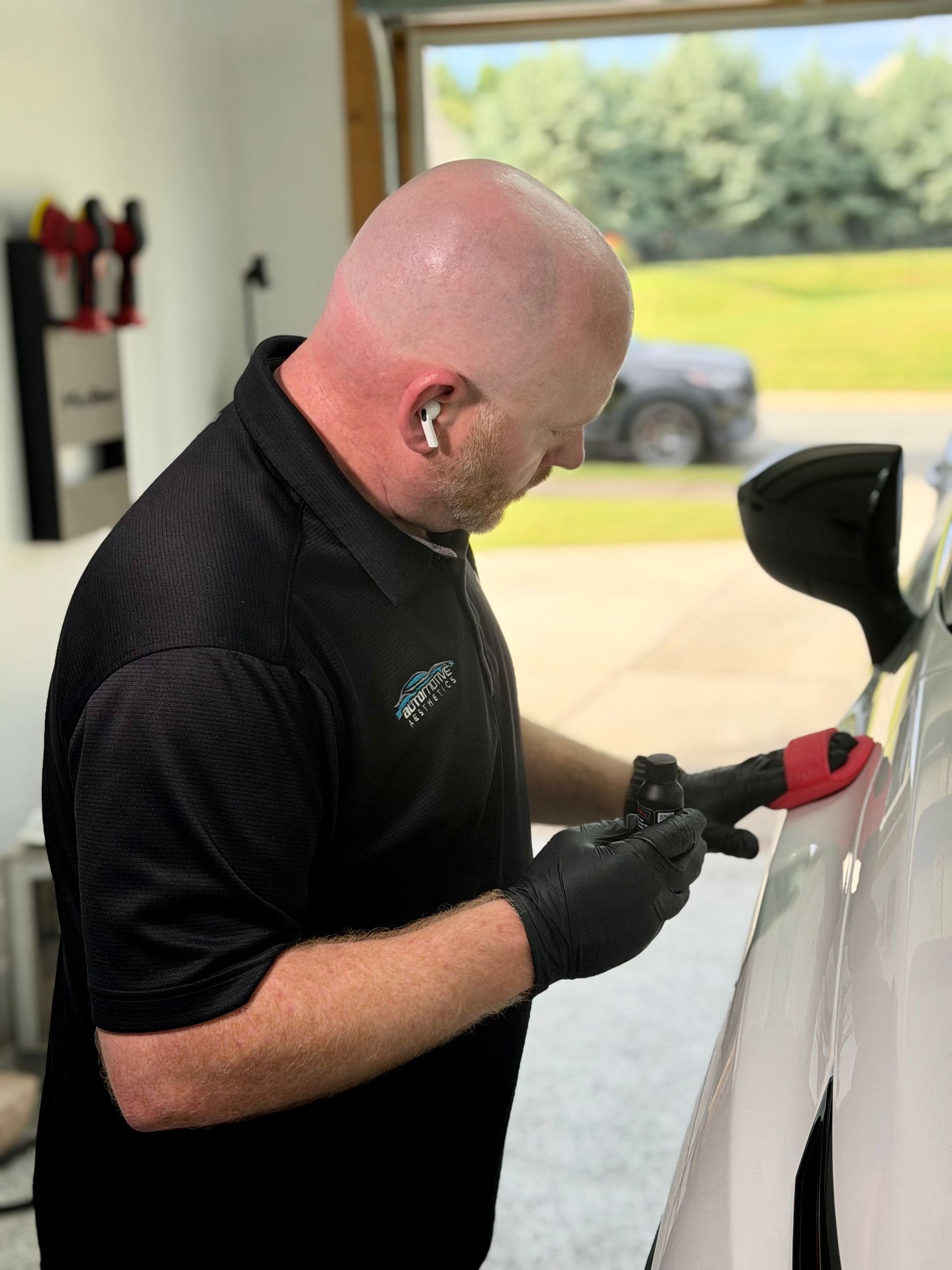 a person wearing black gloves is polishing the hood of a car .
