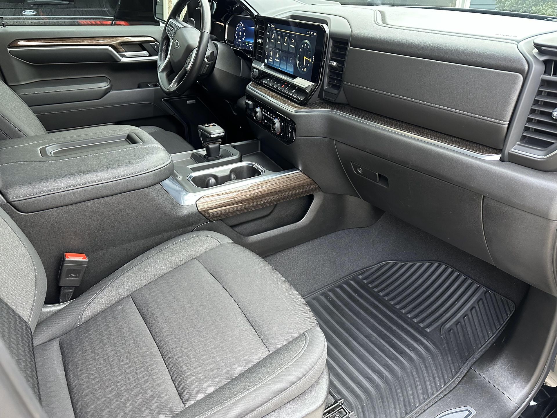 Interior of a black truck; seats, console, dashboard, and floor mat.