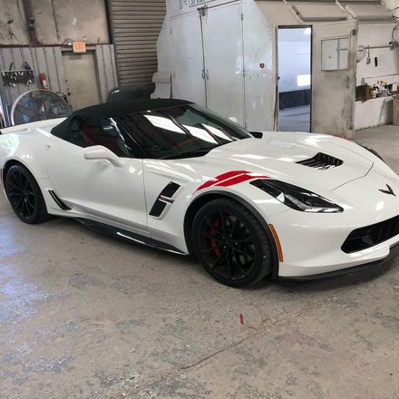 White Corvette convertible with black accents and red stripe.