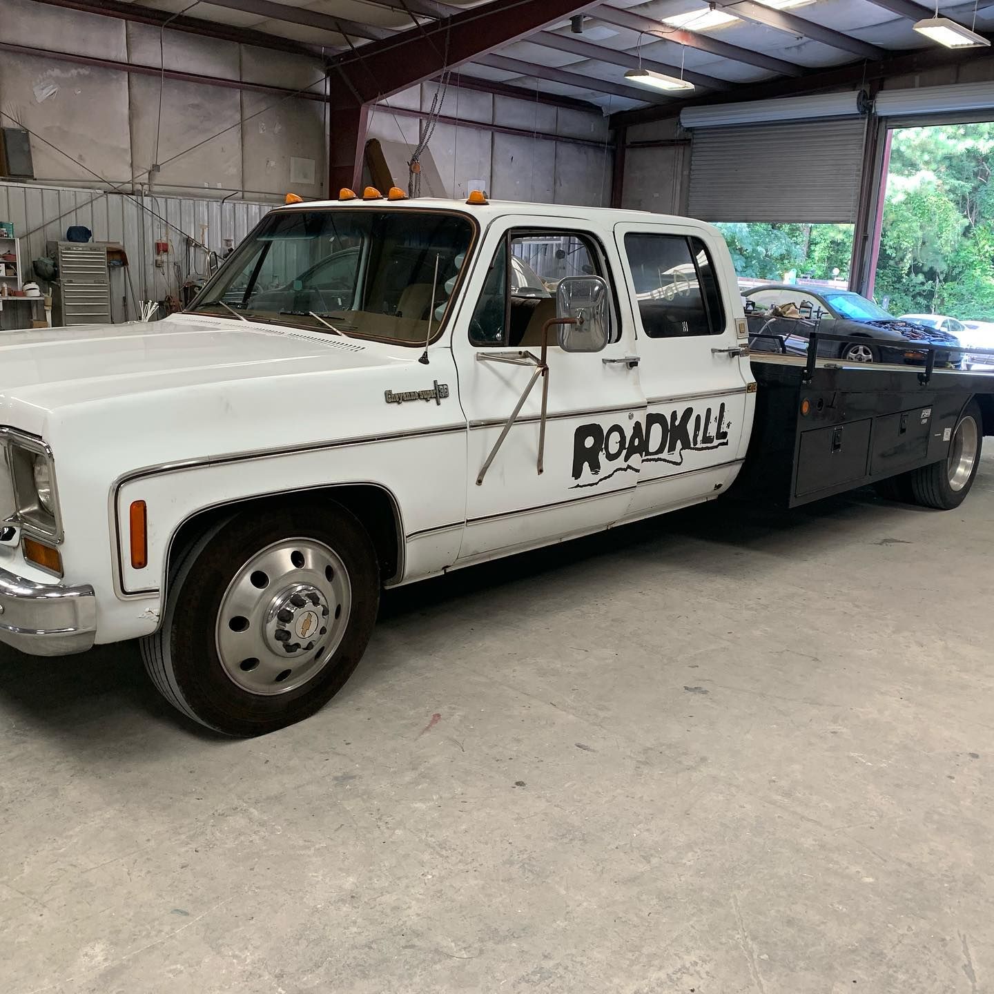 White Roadkill Chevrolet dually flatbed truck inside a garage.