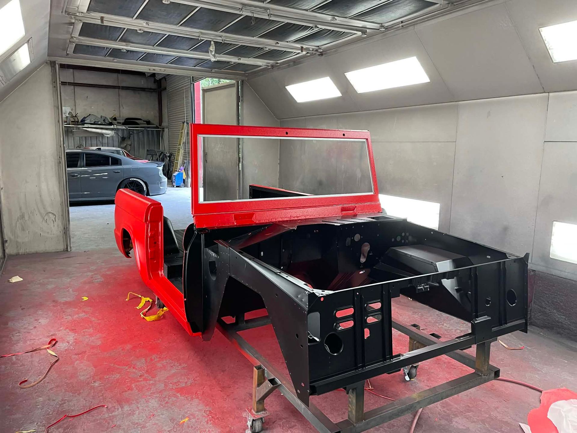 Partially restored black and red car body in a workshop, with a red frame outline and exposed chassis