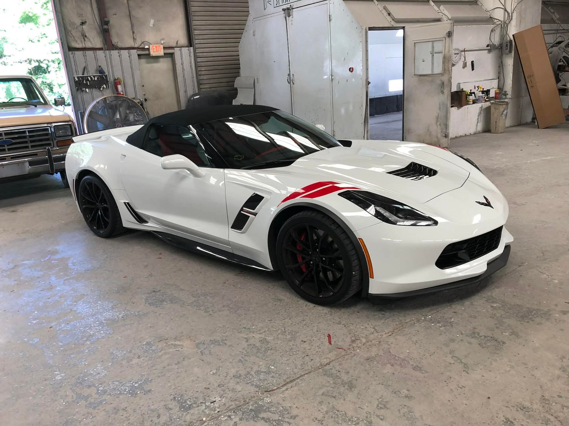 White sports car with black accents parked in an industrial garage