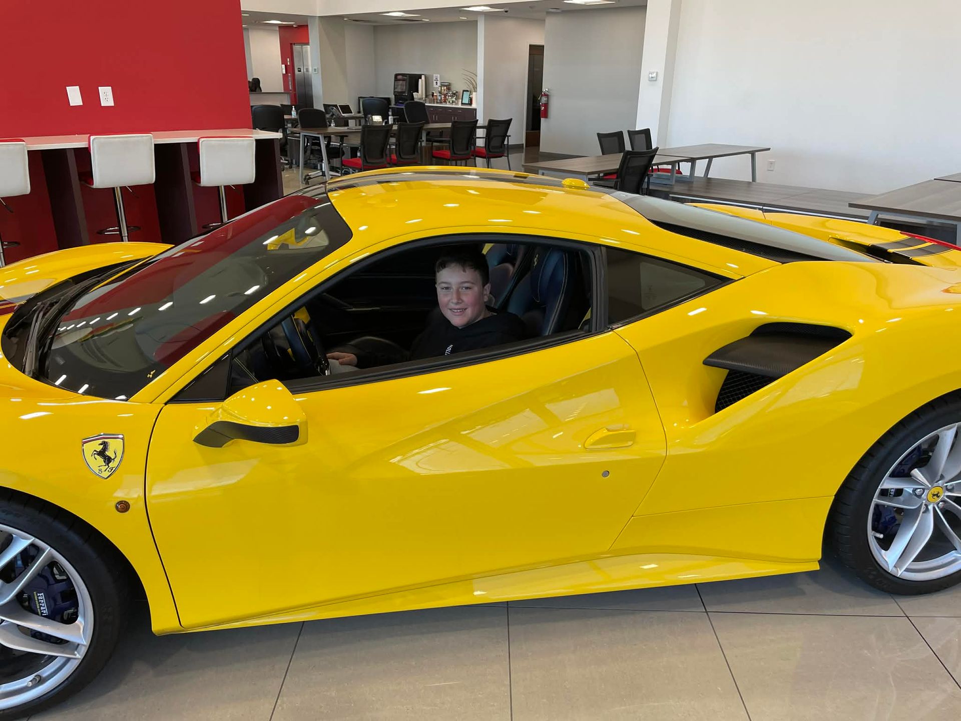 Yellow Ferrari sports car indoors with a person sitting in the driver’s seat