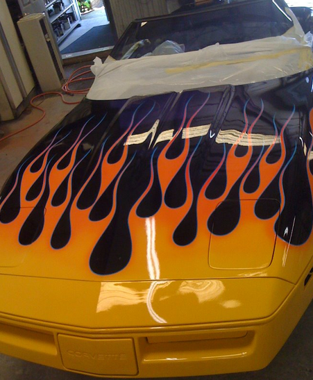 Yellow Corvette with flame paint design on the hood. Black flames with orange and pink details.