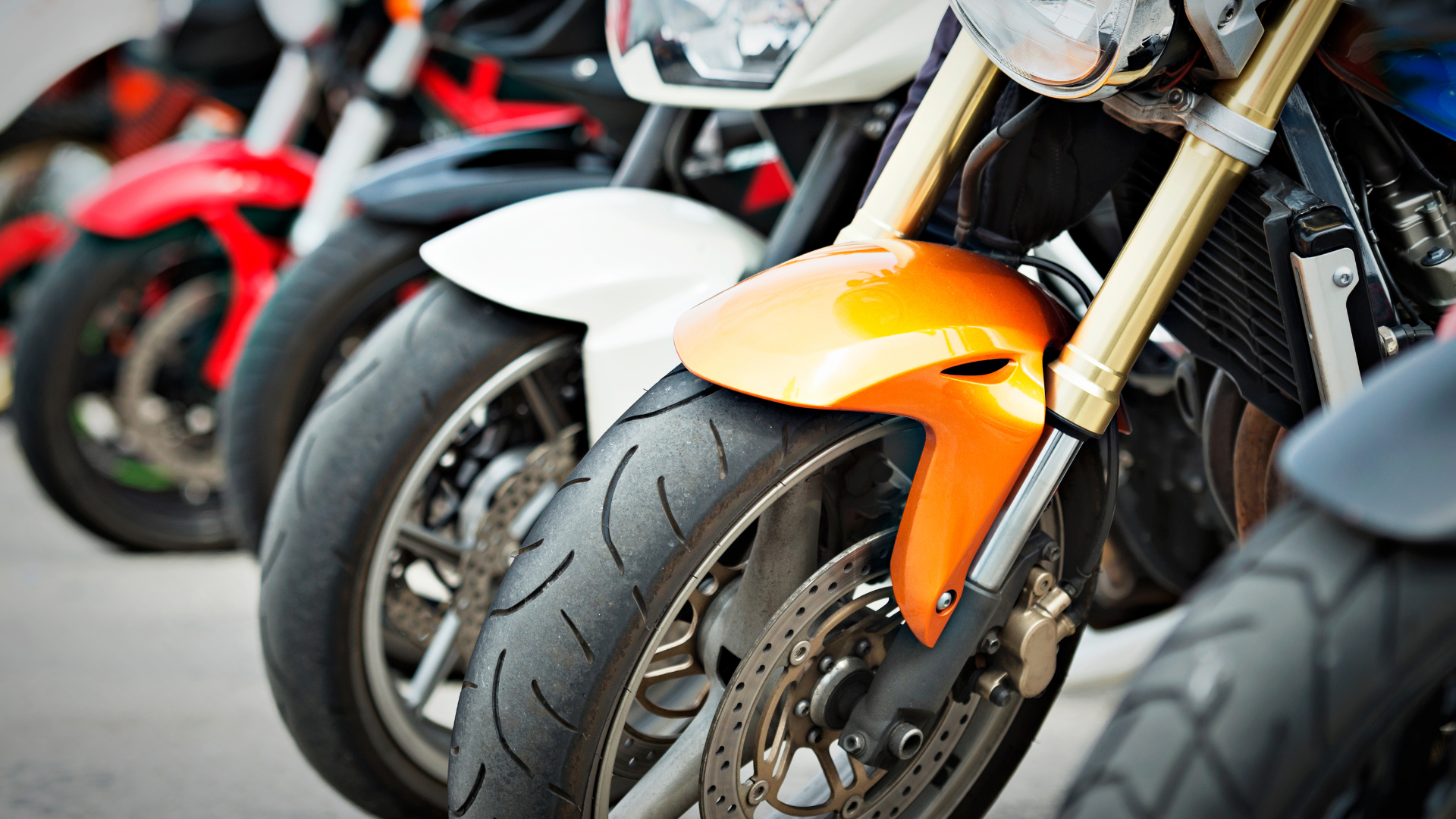 Motorcycle tires and front ends lined up; orange, white, and red visible.