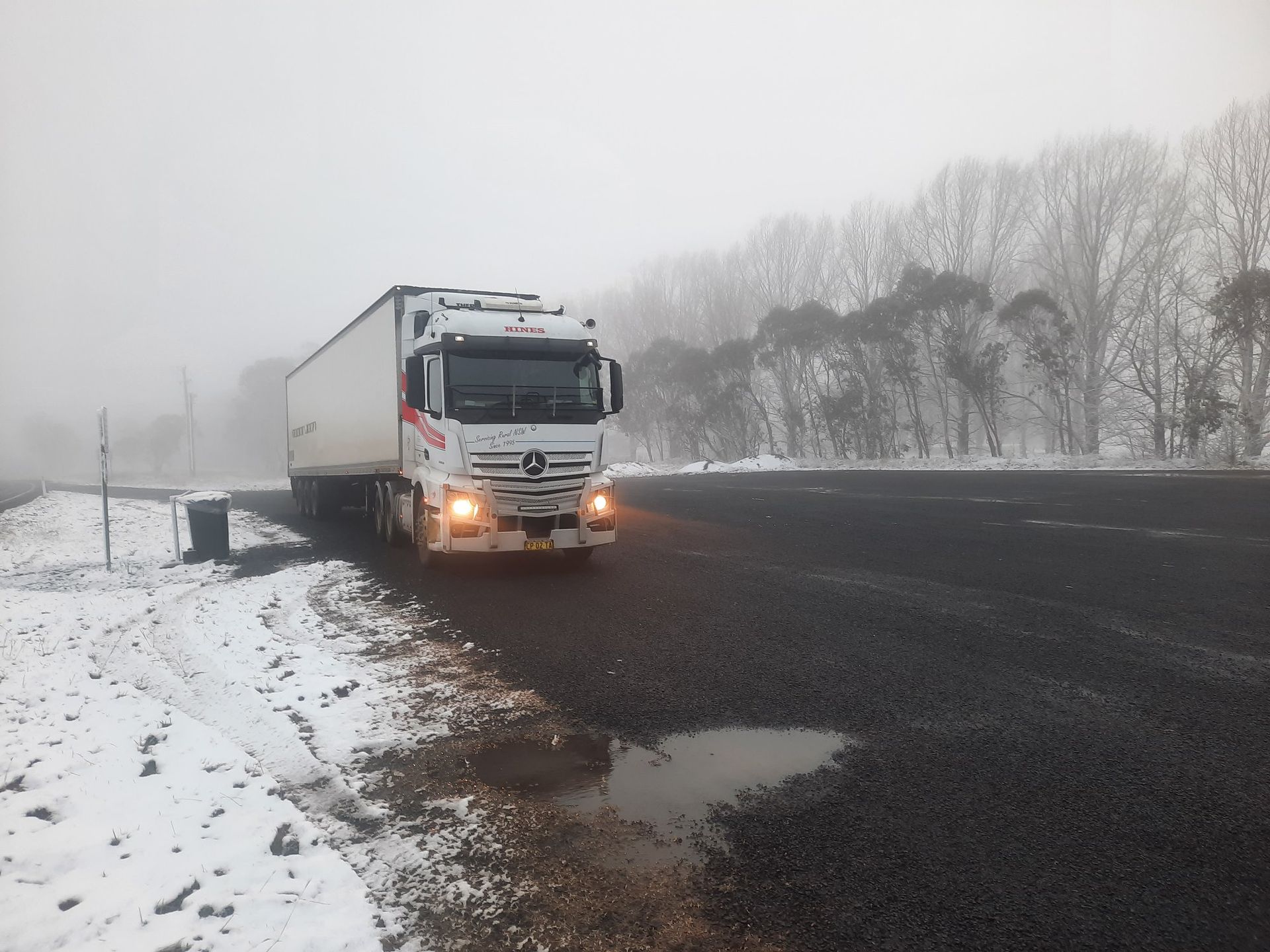 White Semi-truck Driving on a Snow-covered Road in Foggy Conditions — Hines Logistic Pty Ltd In Brisbane, QLD