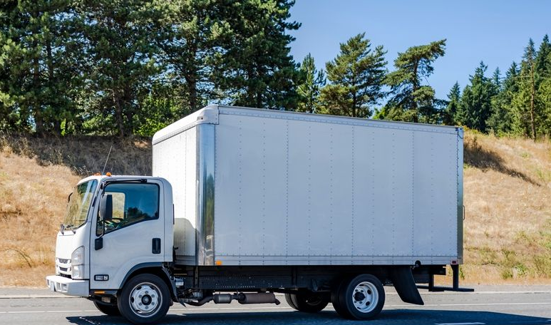 White Box Truck Driving on a Paved Road Next to a Hill With Trees — Hines Logistic Pty Ltd In Inverell, NSW