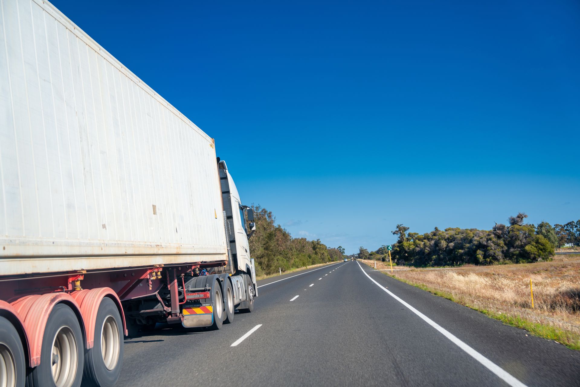 White Semi-truck Driving on a Highway, Clear Blue Sky Overhead — Hines Logistic Pty Ltd In Taree, NSW