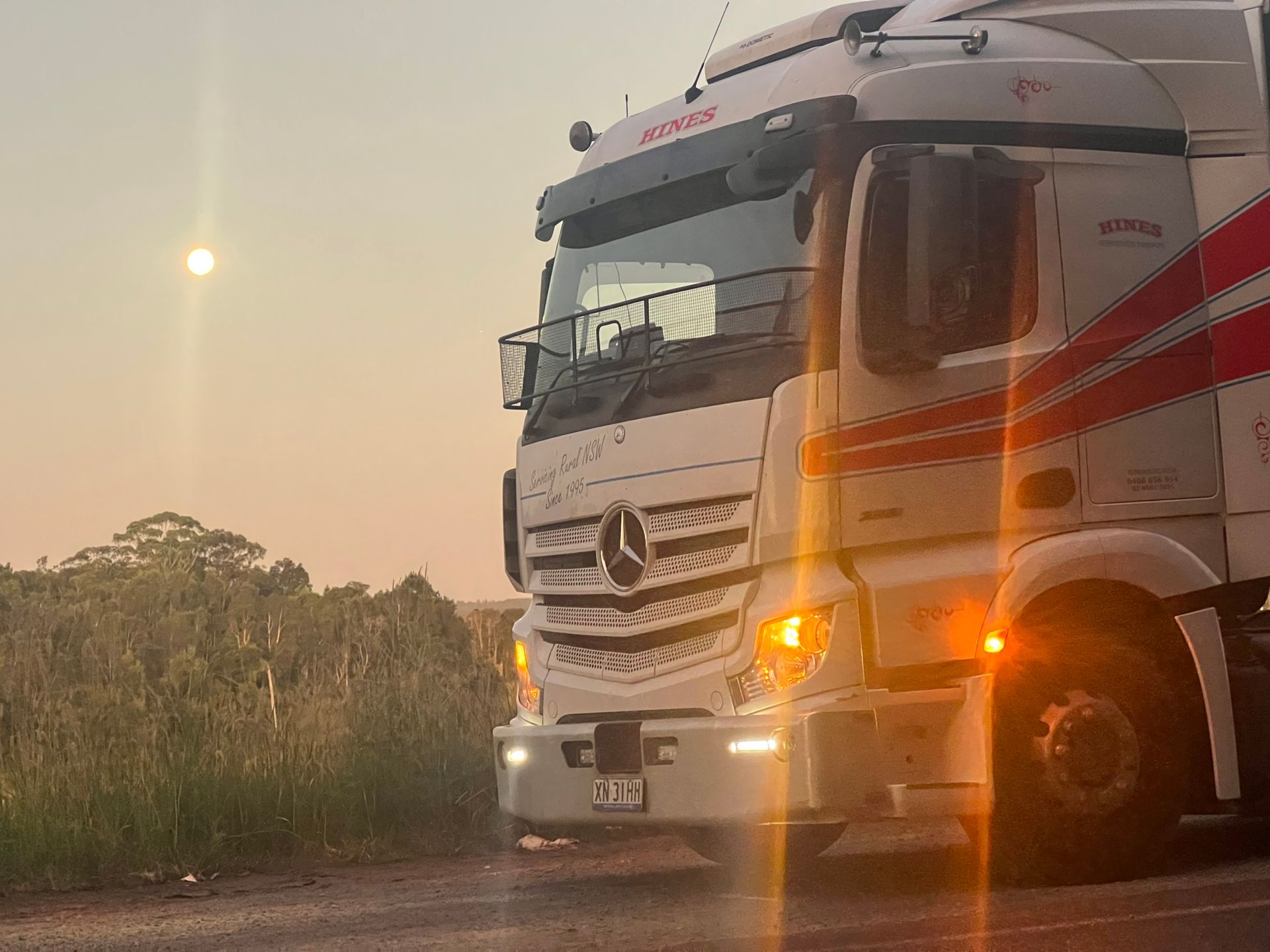 White Semi-truck With Red Stripes Parked on a Road at Dusk — Hines Logistic Pty Ltd In Kundabung, NSW