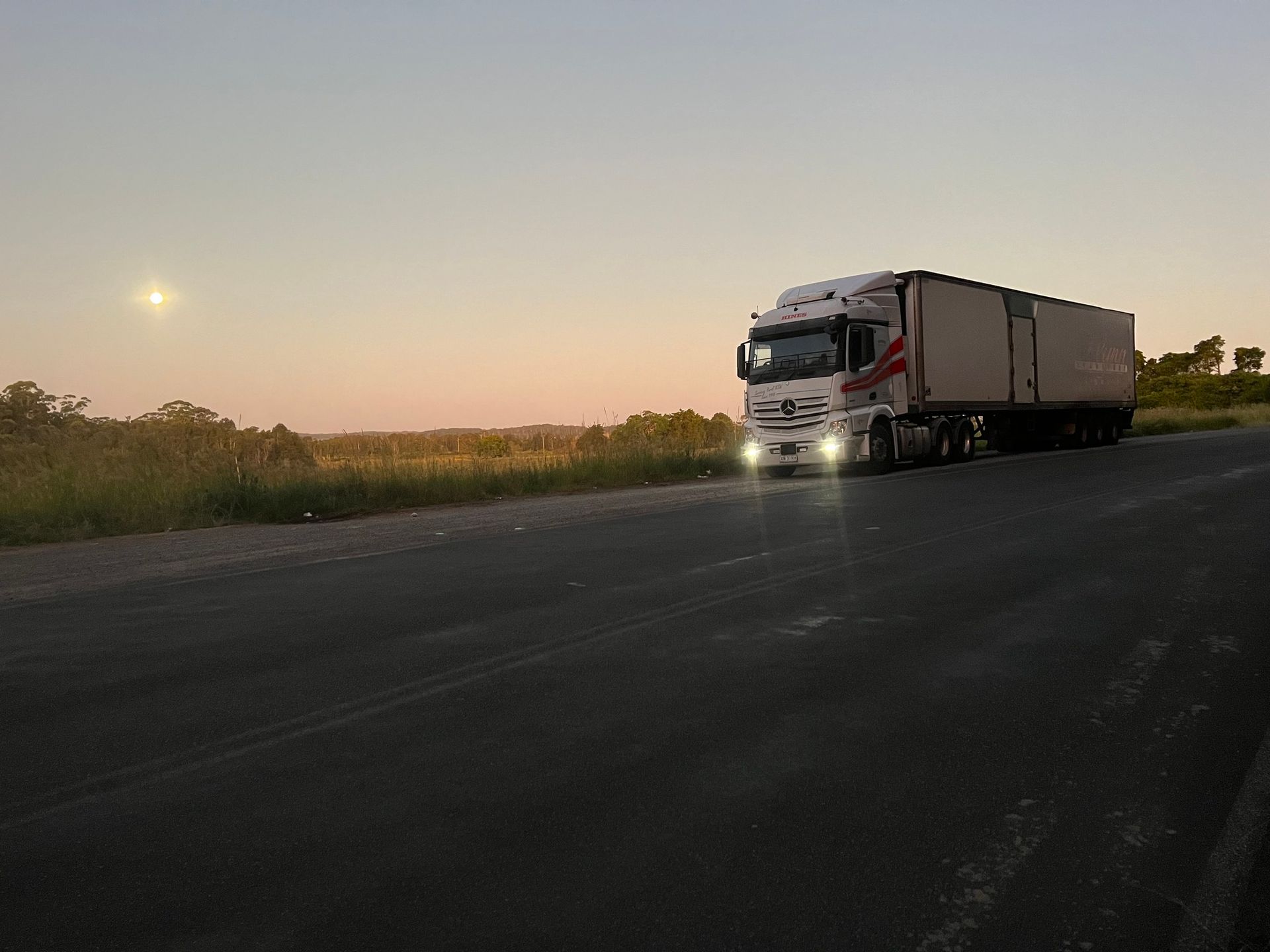 Semi-truck Parked on a Road at Dusk With Lights on, Moon in the Sky — Hines Logistic Pty Ltd In Kundabung, NSW