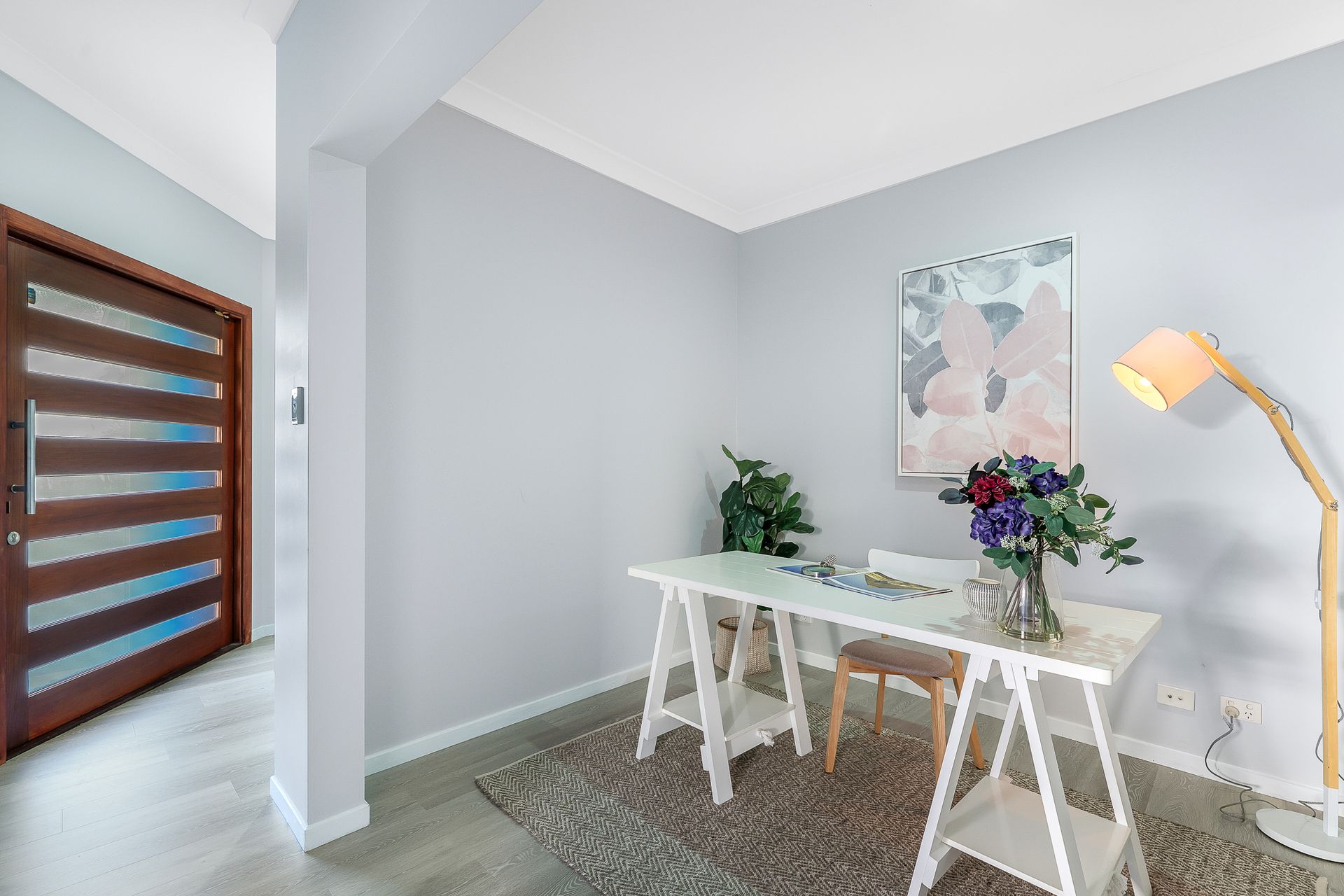 There is a desk with a vase of flowers on it in the room.