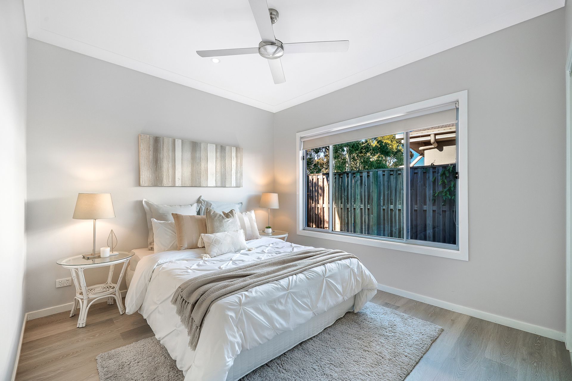 A bedroom with a bed , nightstand , ceiling fan and window.