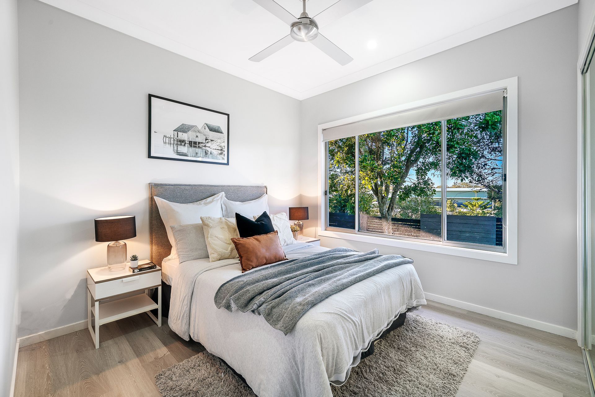 A bedroom with a bed , nightstand , lamps and a ceiling fan.