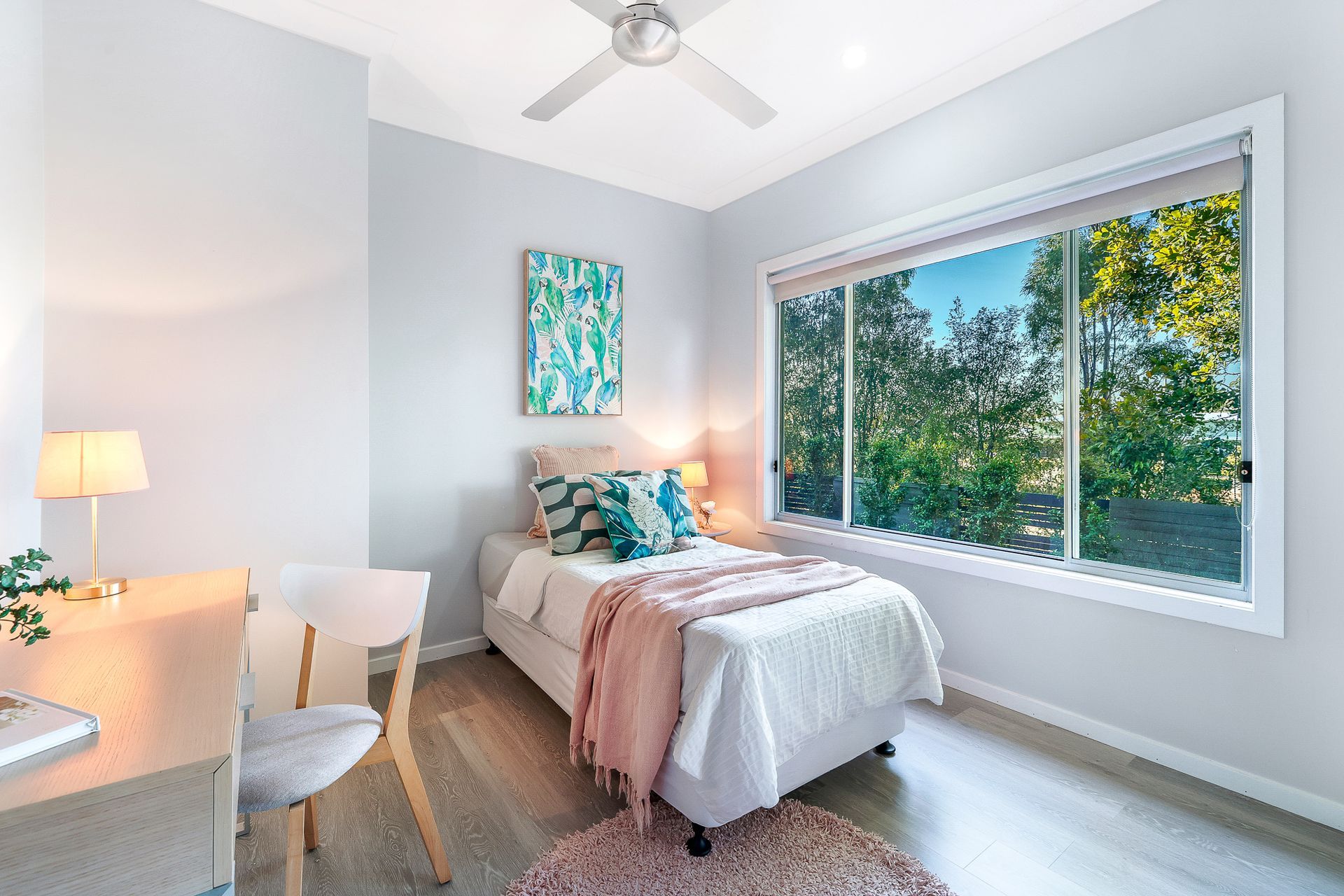 A bedroom with a bed , desk , chair and ceiling fan.